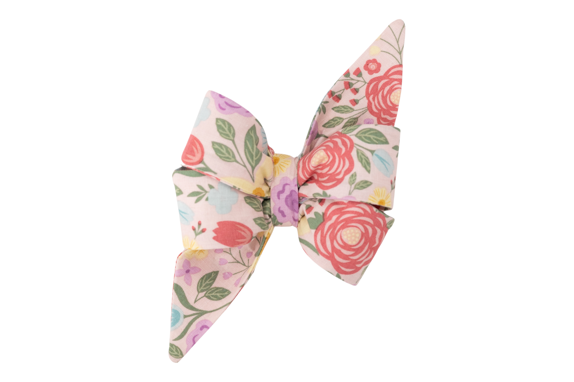 Handcrafted girl dog belle bow in light pink fabric, covered in a lush garden pattern of large red flowers, tulips, and mixed floral elements in purple, yellow, and blue.