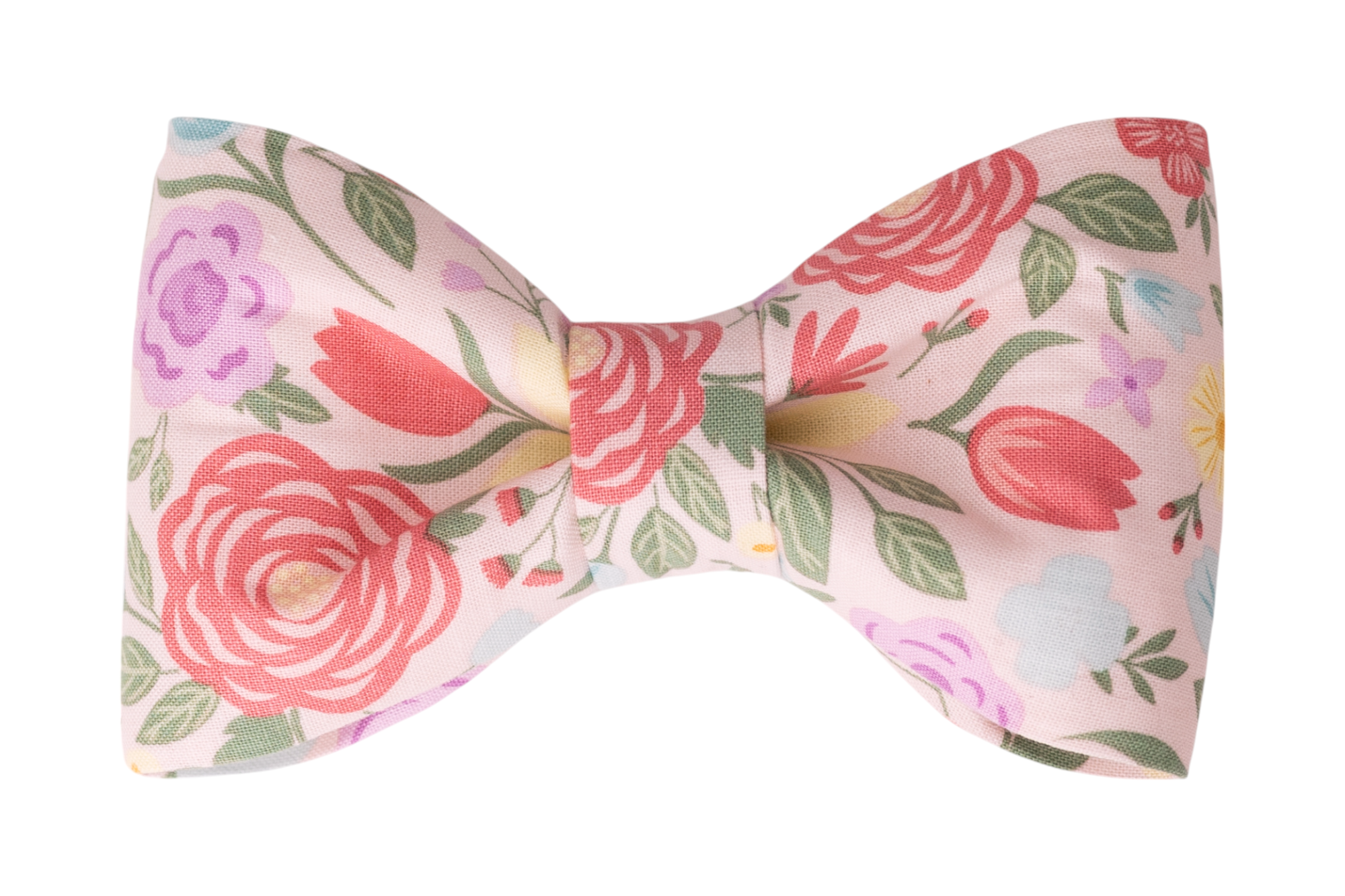 Handcrafted dog bow tie in light pink fabric, covered in a lush garden pattern of large red flowers, tulips, and mixed floral elements in purple, yellow, and blue.