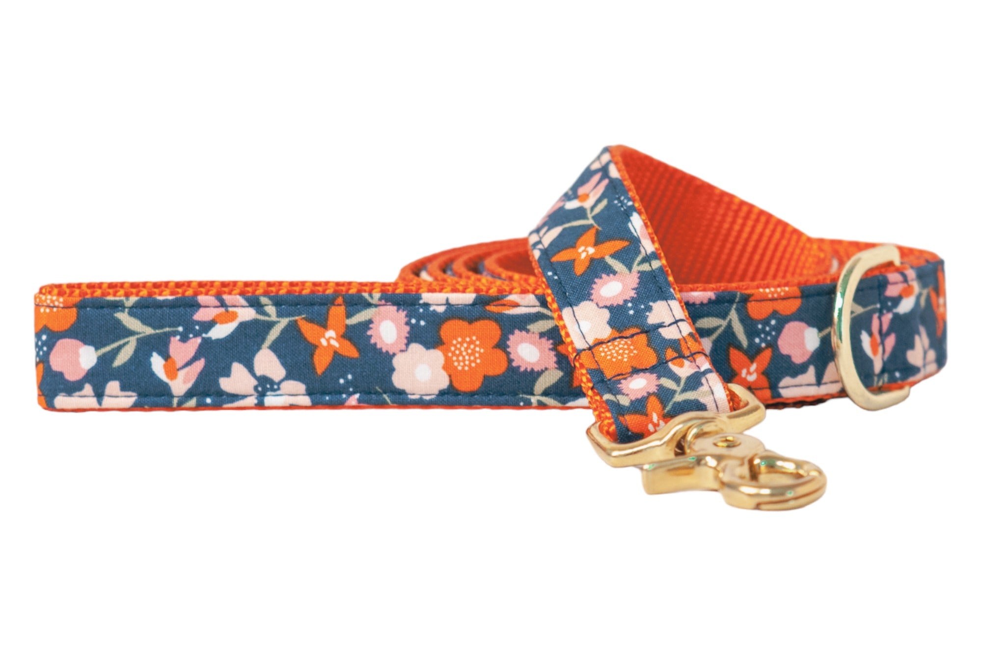Dog leash with a dark navy blue fabric with a fall floral pattern featuring small blossoms and leafy stems. The fabric is stitched over sturdy nylon webbing and the leash is finished with a polished swivel clasp and a matching D-ring near the handle.