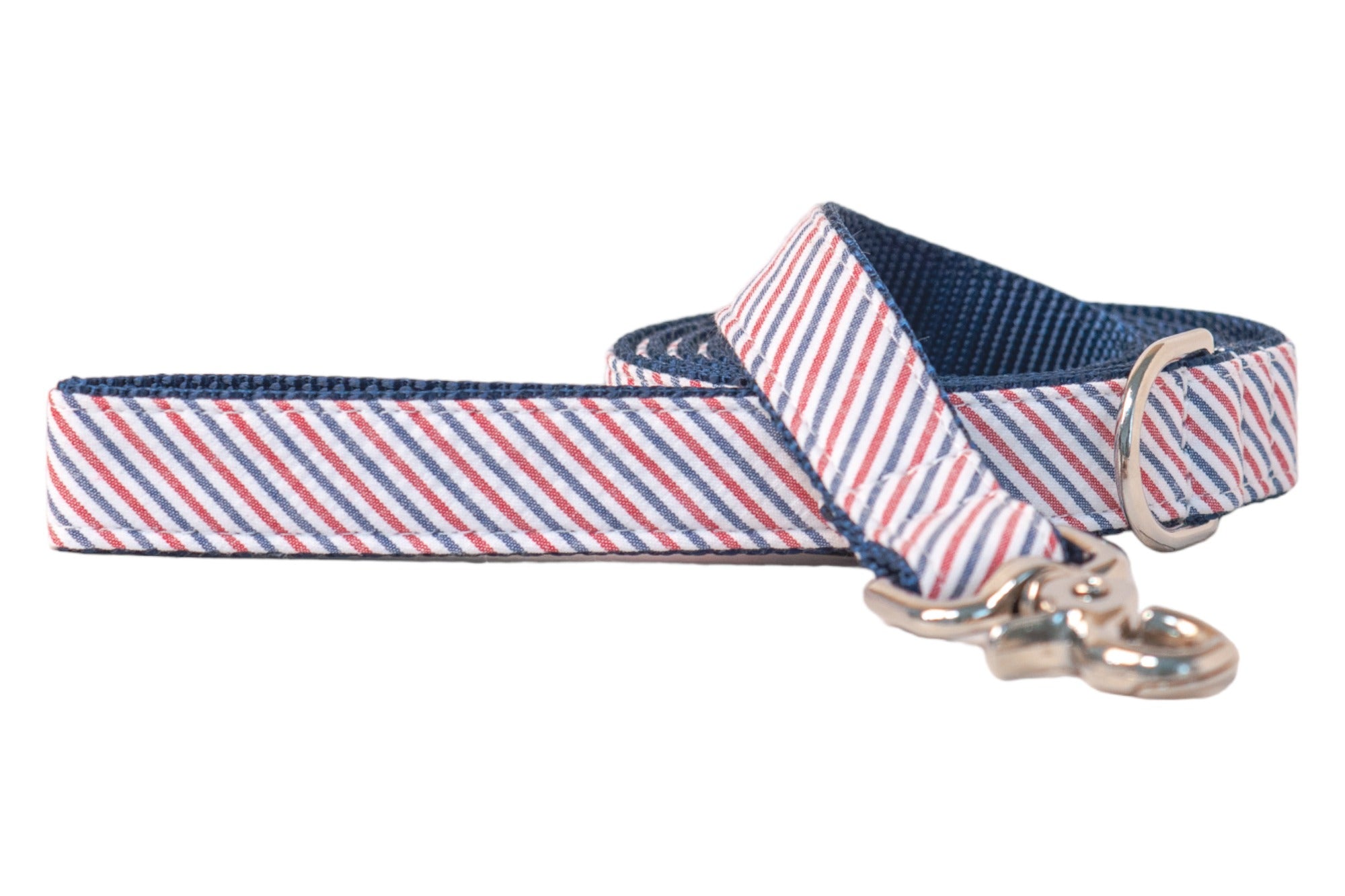 Patriotic-themed pet leash with diagonal red and blue seersucker on white fabric, navy blue lining, and metal clip and D-ring for secure fastening.