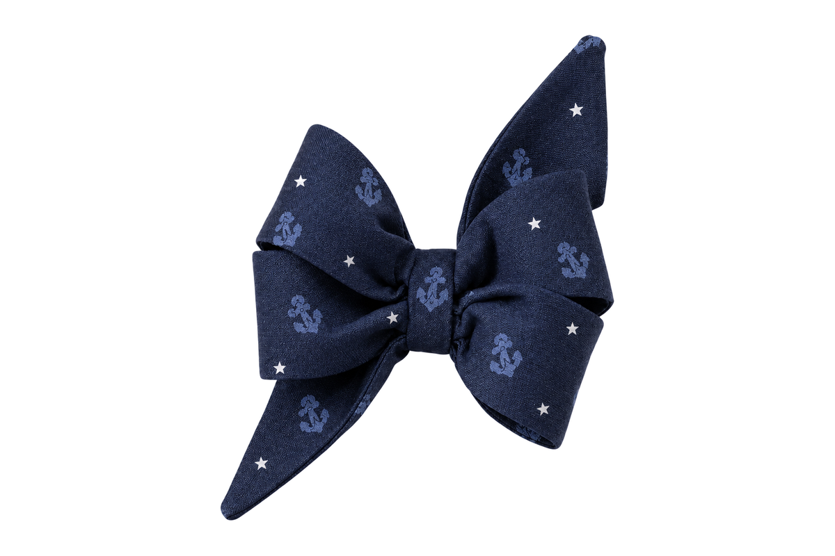 Standalone belle bow in Anchors Away fabric, a navy blue fabric with small tonal periwinkle blue anchors and tiny white stars, with full upright loops and two pointed tails, photographed on a white studio background.
