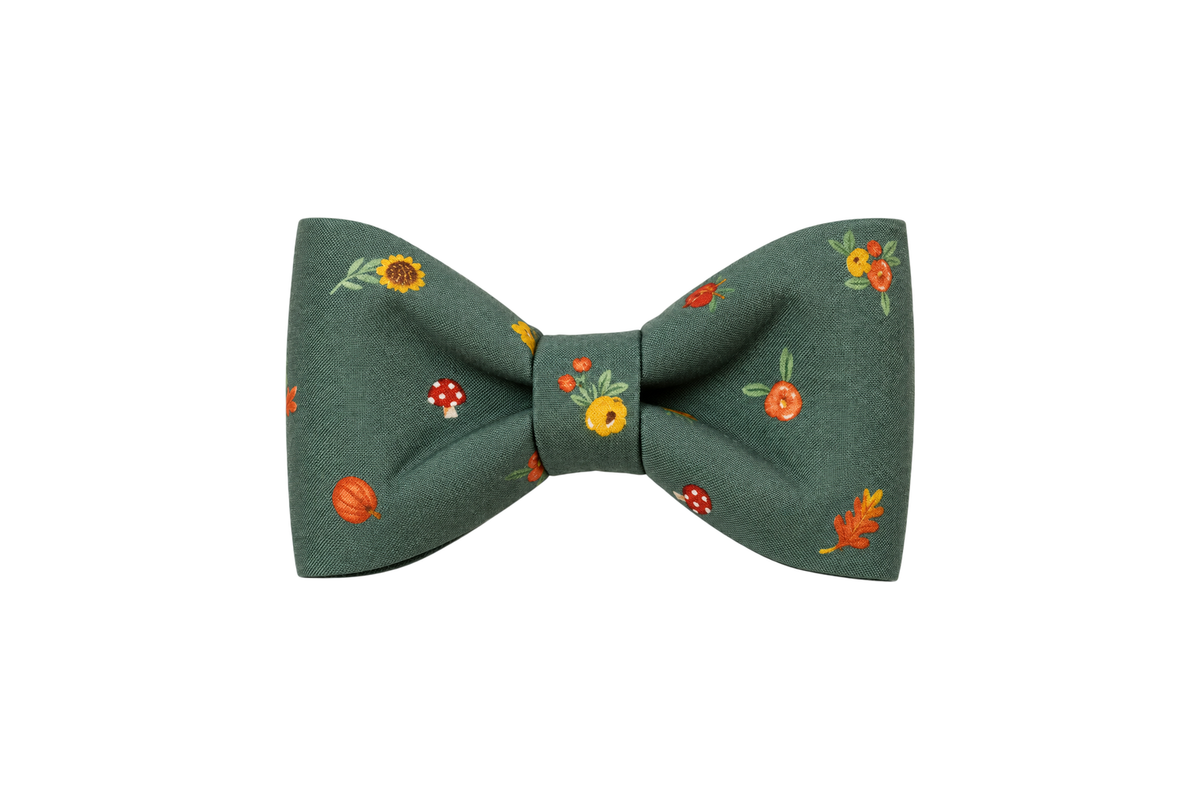 Classic dog bow tie in Autumn Blooms fabric, a muted sage green fabric with small scattered orange, red and golden yellow fall flowers, with a matching fabric center knot, photographed on a white studio background.