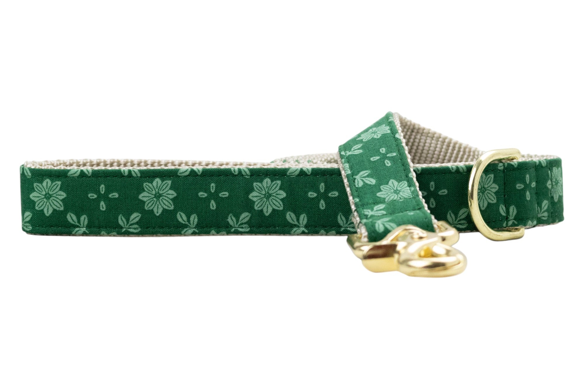 Dog leash made from green fabric with a repeating light green floral pattern, featuring symmetrical flower and leaf designs. The leash is lined with nylon woven webbing for durability and finished with metal hardware, including a swivel clasp and a D-ring near the handle.