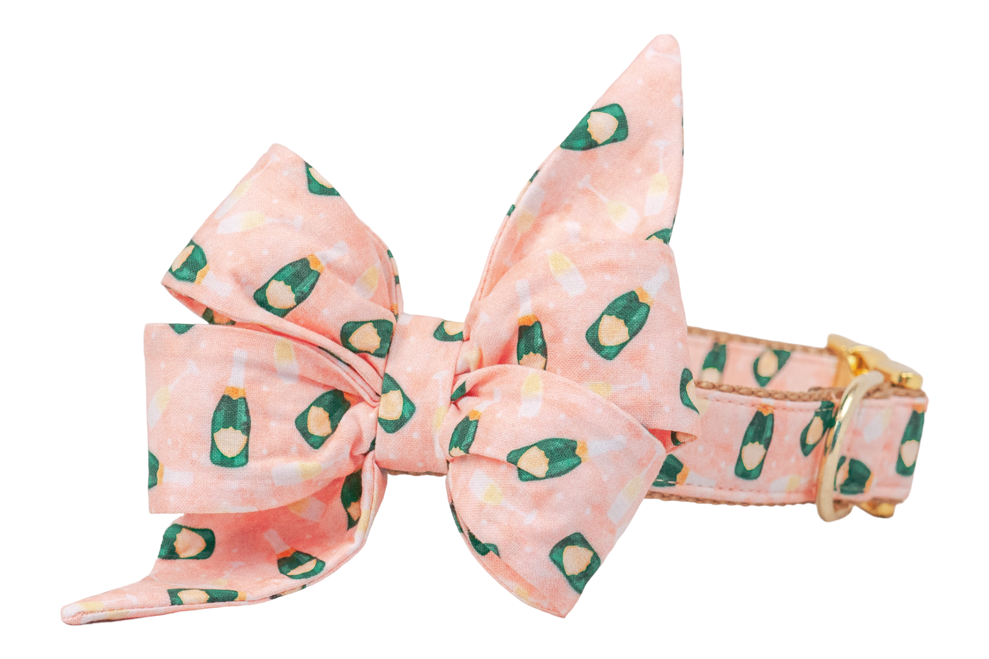 A large decorative dog belle bow attached to a dog collar, both have blush pink fabric patterned with miniature green champagne bottles and filled glasses. The bow features dramatic, pointed tails and full, structured loops, creating a statement look. The collar includes gold hardware and reinforced stitching, blending style with durability.