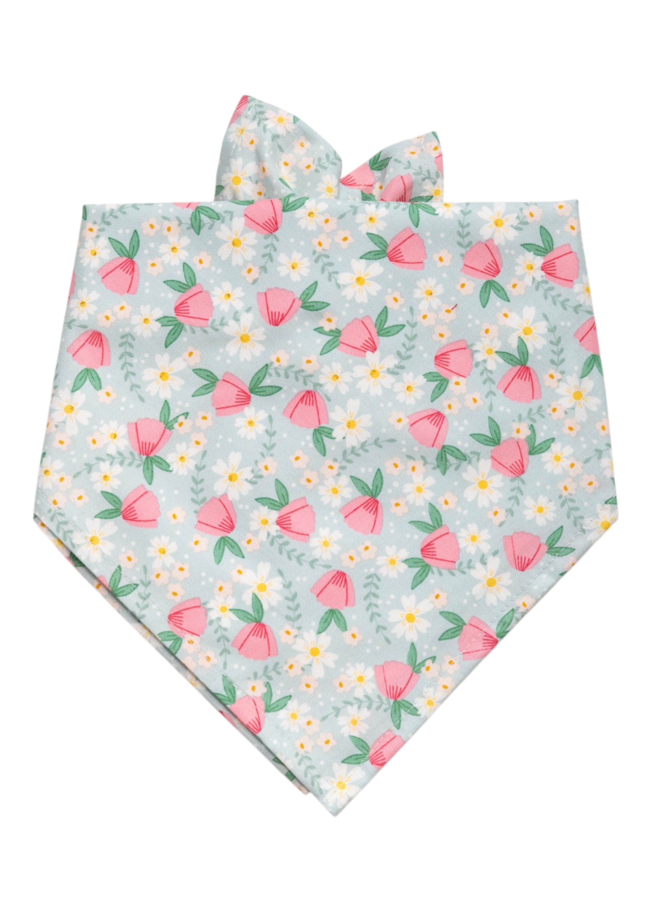 Pastel wildflower dog bandana with pink flowers, white daisies, and green leaves on a soft blue background.