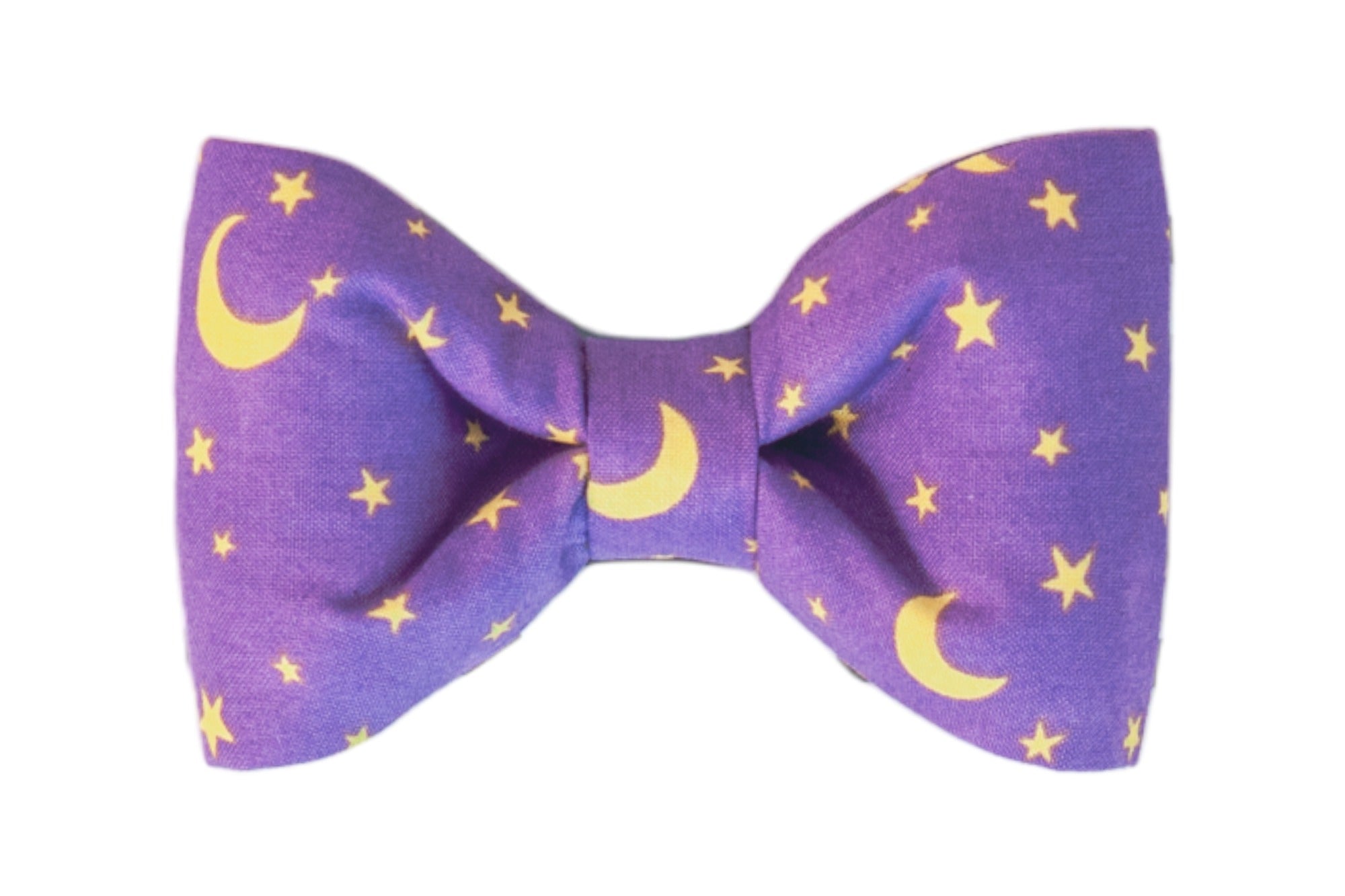 A purple dog bow tie featuring a celestial pattern of stars and crescent moons on soft fabric. The bow tie has a classic, symmetrical shape with a central knot and curved edges. A charming and versatile accessory, ideal for Halloween or stargazing-themed looks.