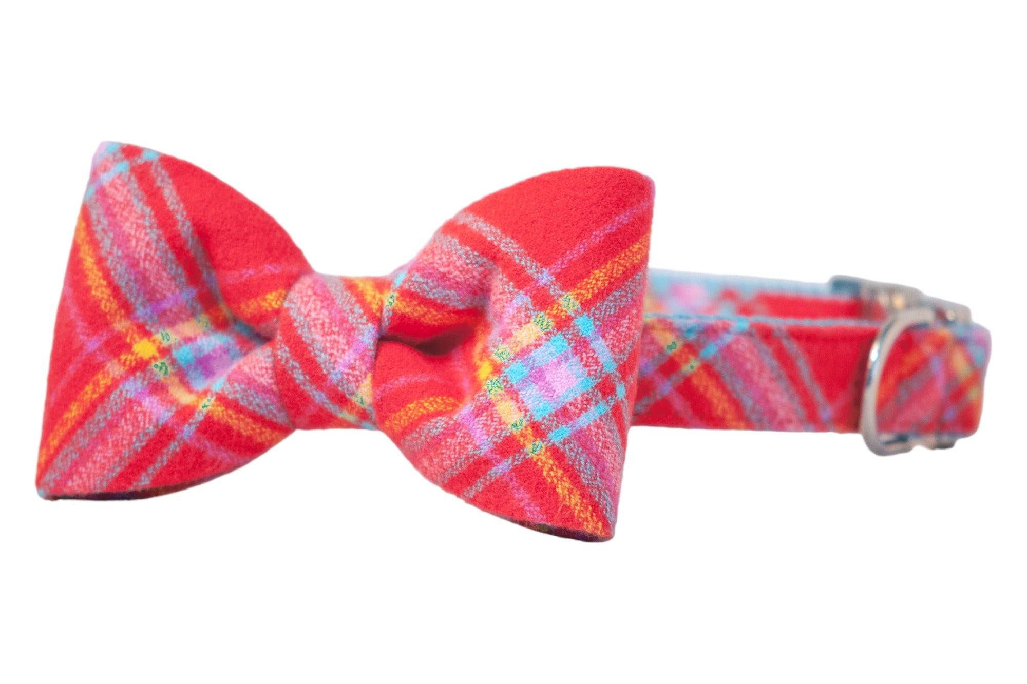 A red flannel dog collar featuring an attached, matching, and structured bow tie with a vibrant plaid pattern of overlapping lines. The collar includes a metal D-ring on the right side.