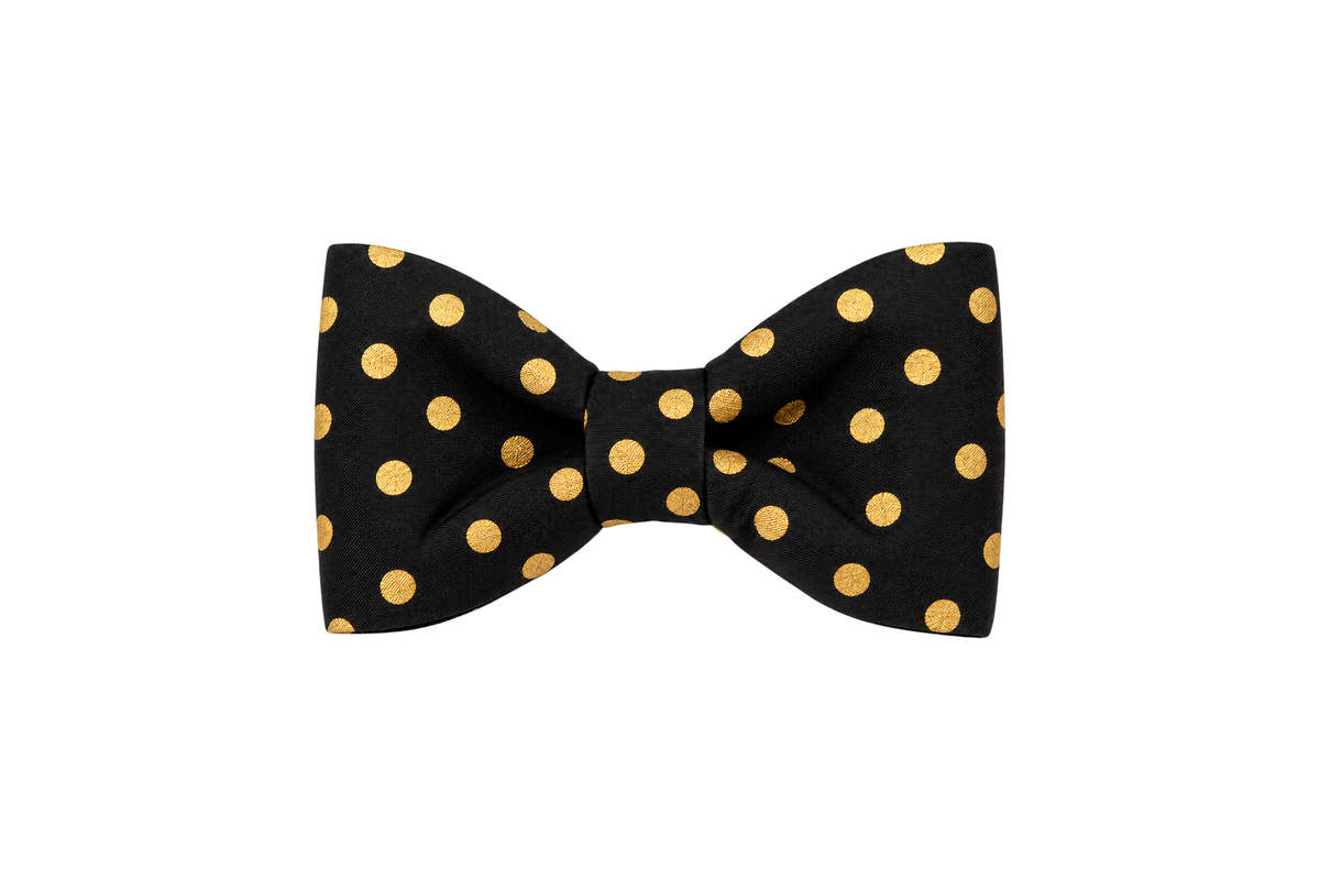 Classic dog bow tie in Black Party Dot fabric, a black fabric with metallic gold polka dots, with a matching fabric center knot, photographed on a white studio background.