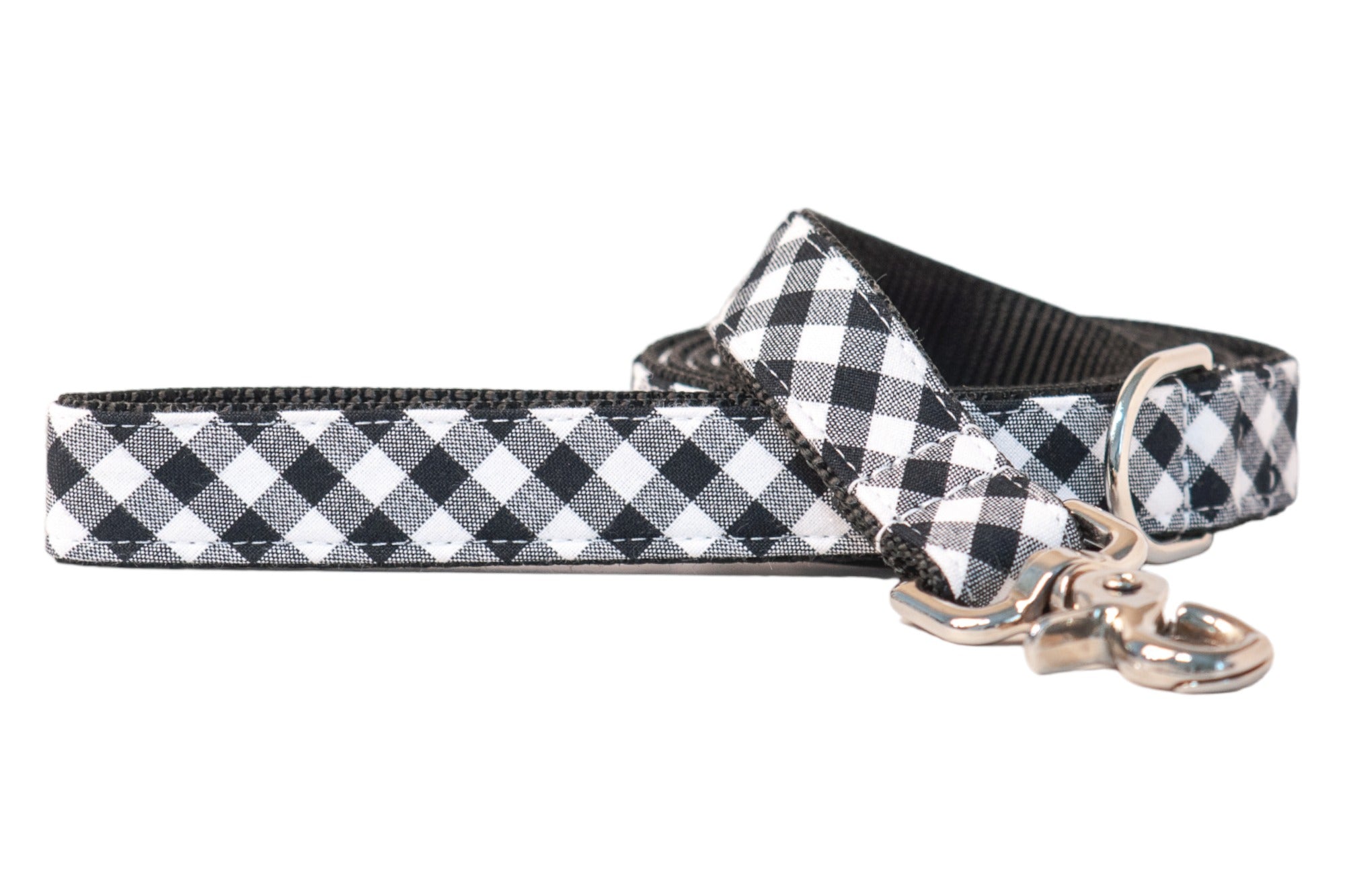 Dog leash featuring a black picnic plaid pattern with a soft black woven underside. Designed with reinforced stitching, a swivel clasp and a matching D-ring near the handle. A versatile accessory that adds a timeless charm to walks.