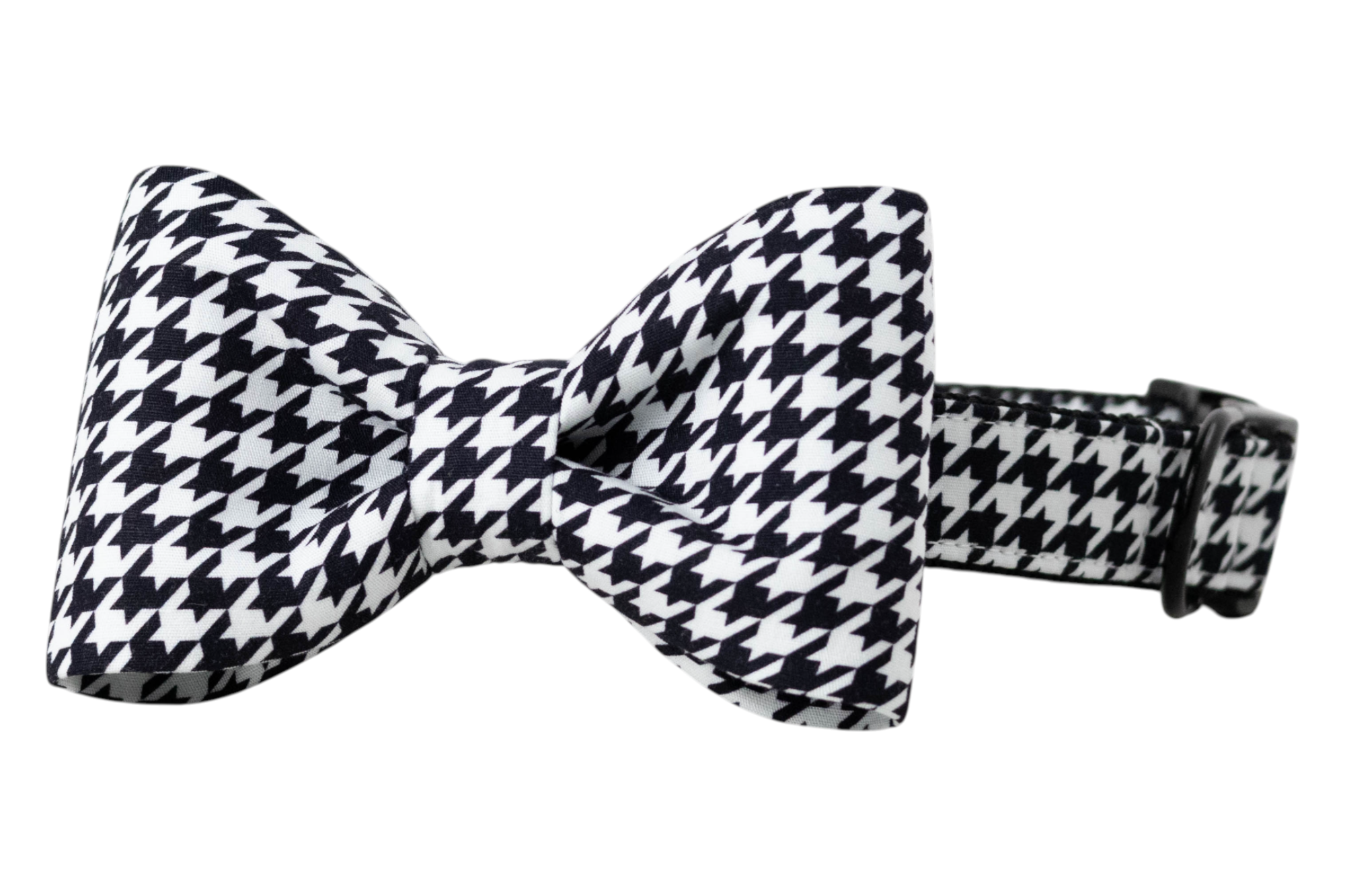 A dog collar with a classic black and white houndstooth pattern, featuring an attached fabric bow tie in the same print. The bow tie is neatly structured with symmetrical loops and a center knot, creating a polished, tuxedo-style look. The collar includes black adjustable hardware and reinforced stitching for durability and style.