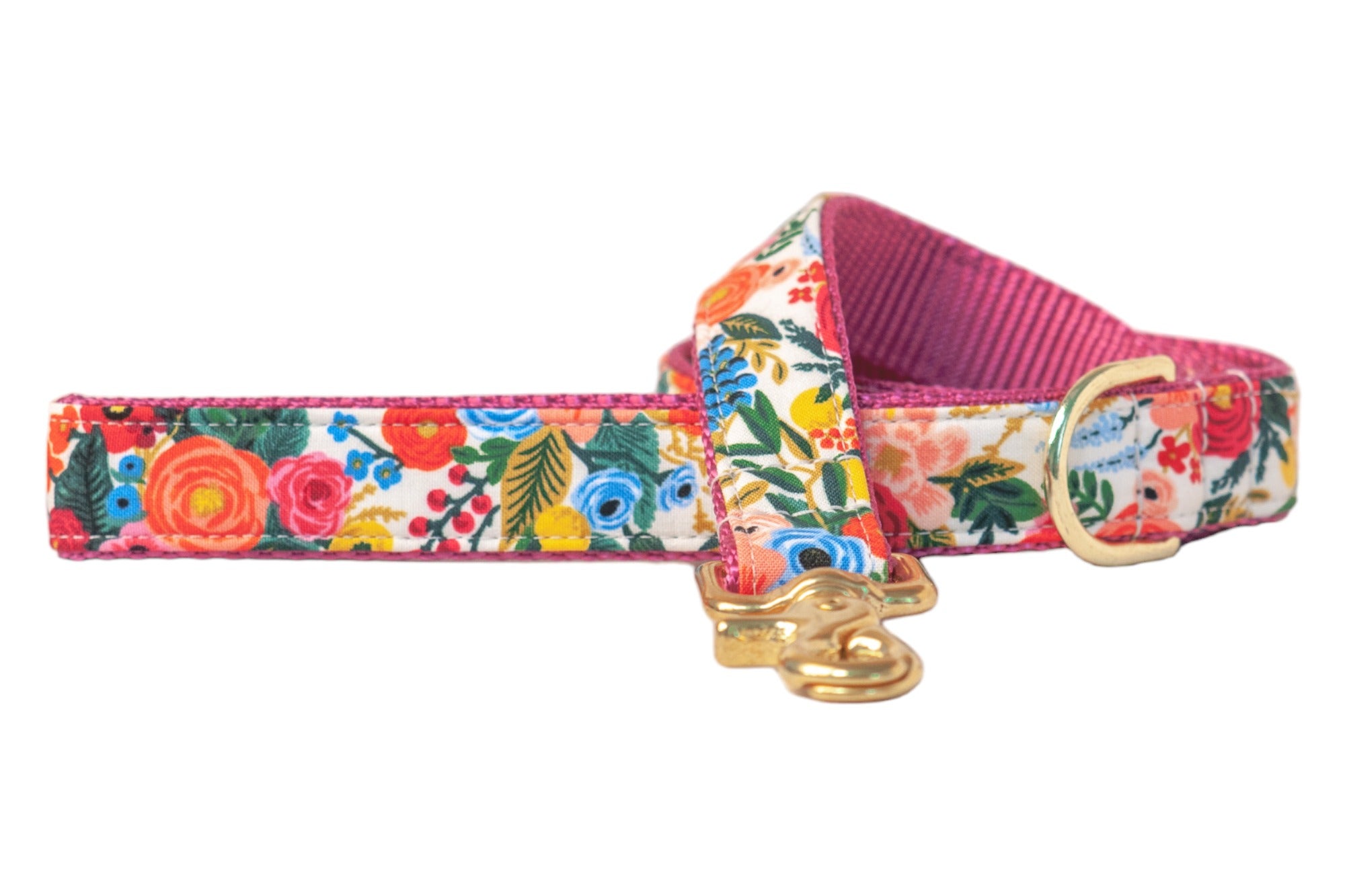 A colorful dog leash with a bright floral pattern, including various blooms and green leaves. The leash is accented with pink webbing on the interior and edges, and finished with a silver clasp for collar attachment.
