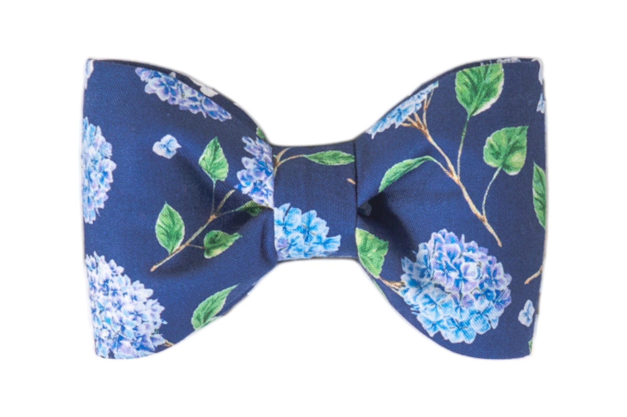 Navy blue fabric dog bow tie featuring a detailed hydrangea floral pattern with light blue blossoms and green leaves.