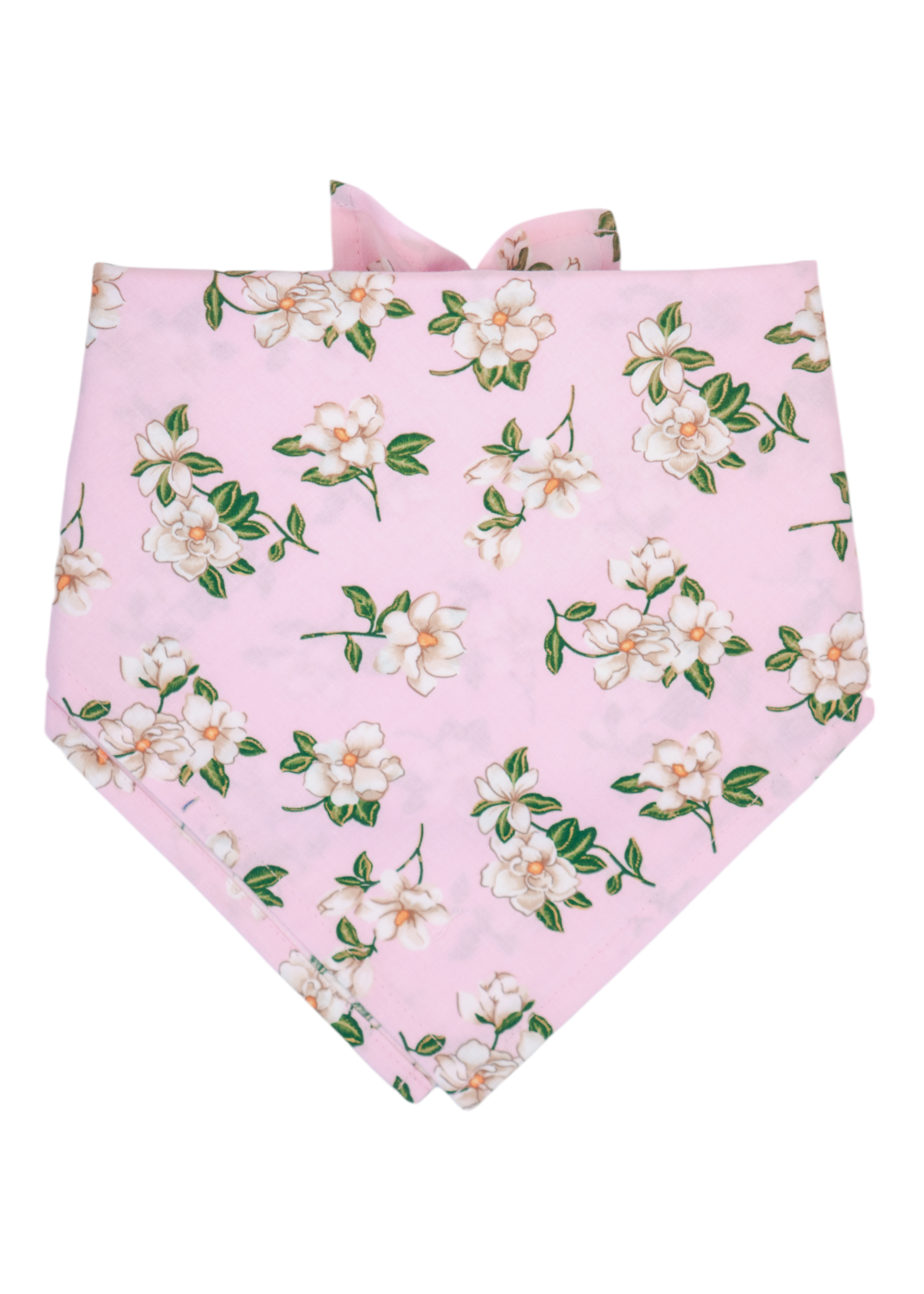 Dog bandana in a soft pink fabric with clusters of white magnolia flowers and leaves. The bandana is folded in a classic triangular shape with neatly stitched edges and ties at the back of the neck. Lightweight and elegant, it offers a romantic, feminine accessory for pets, coordinating with the matching collar and leash in the same floral design.