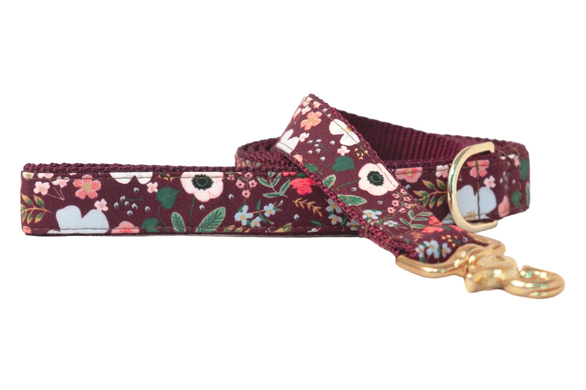 Dog leash with a rich burgundy red fabric with a variety of floral design of blossoms with leaves. The fabric is sewn onto sturdy burgundy nylon webbing with matching stitching, and the leash is finished with a polished swivel clasp and a matching D-ring near the handle.