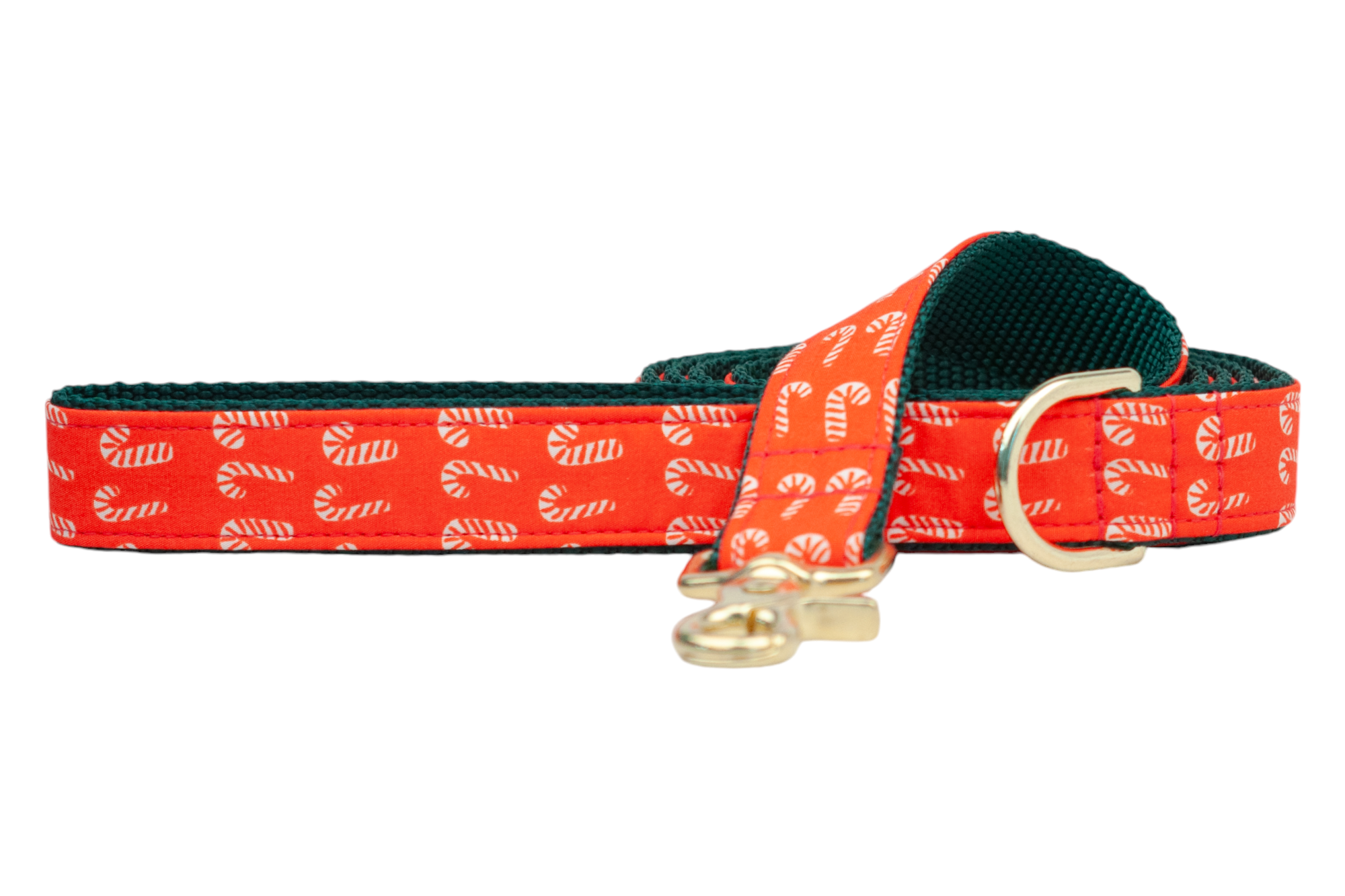 A festive dog leash with a bright red fabric exterior patterned with small candy canes. The leash is lined with woven nylon for added durability and features sturdy hardware, including a swivel snap hook and D-ring near the handle for.