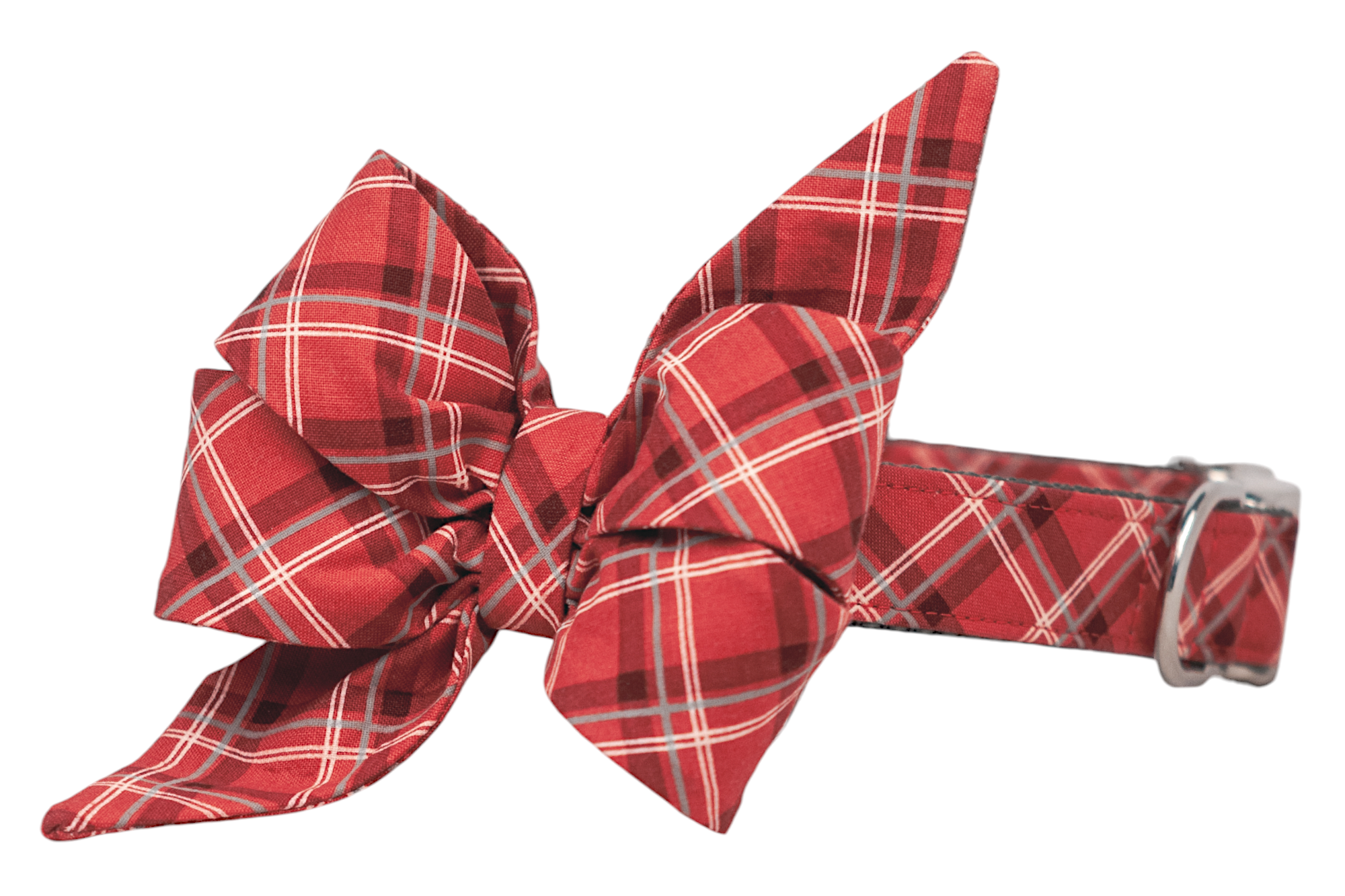 A red tartan-patterned dog collar with a large, multi-petal fabric flower affixed to one side. The adjustable collar is made from matching plaid material and includes a sturdy D-ring for leash attachment. Handmade in Charleston, SC.