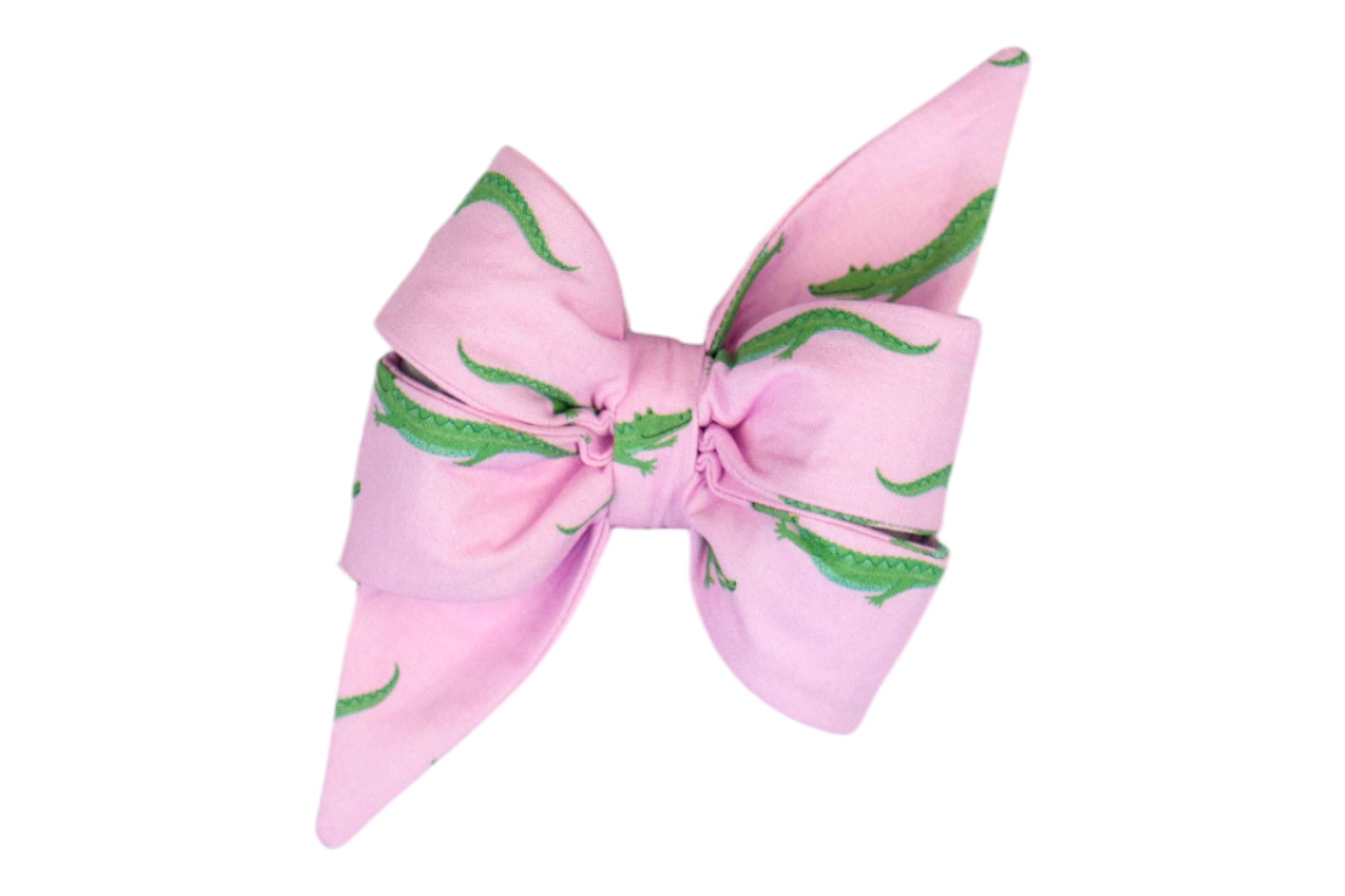 A structured, feminine dog belle bow in light pink, decorated with repeating green crocodile illustrations. The belle bow features clean, curved edges and a cinched center, giving it a crisp, tailored look.