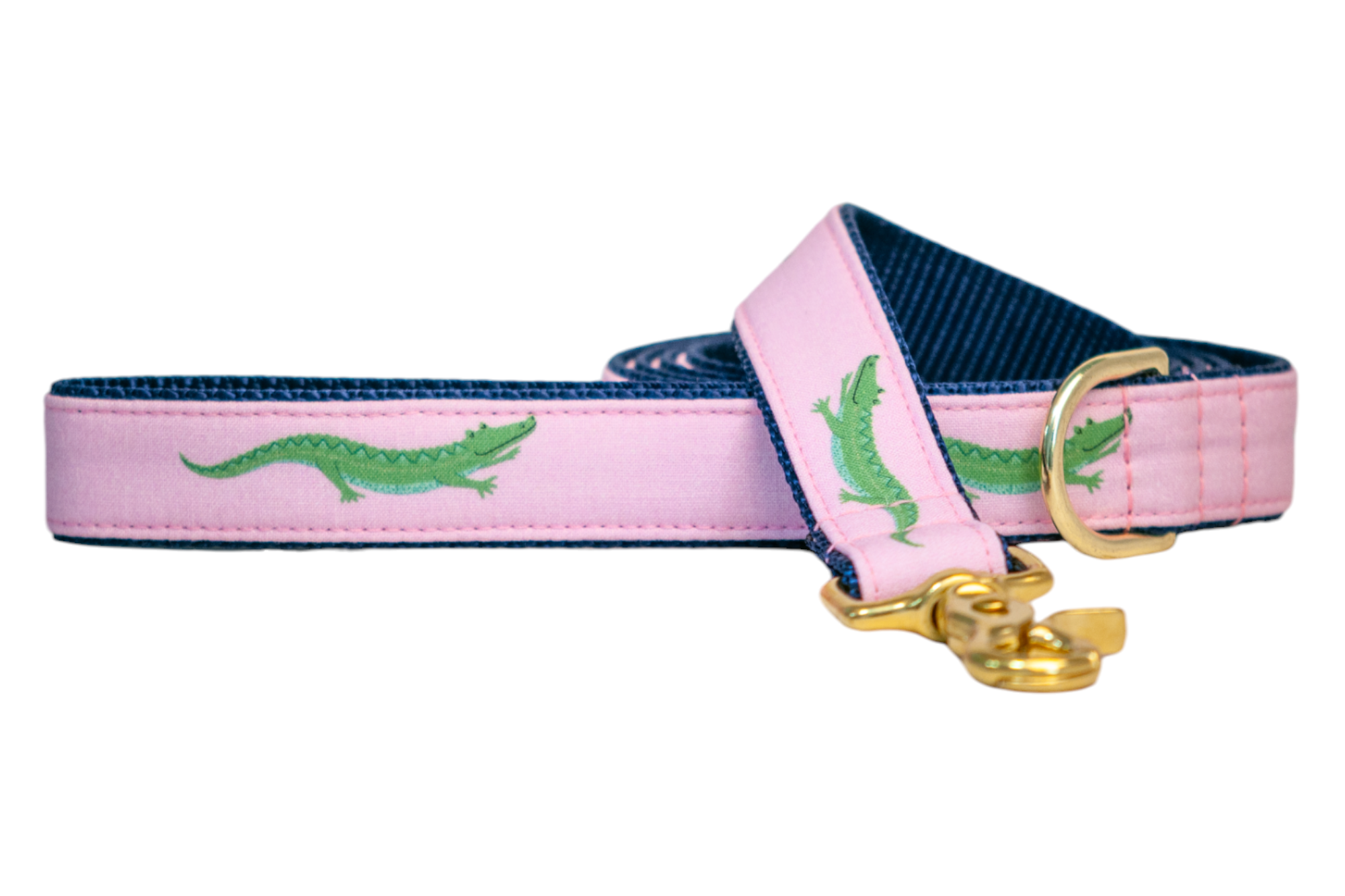 Preppy-style dog leash with whimsical green crocodiles on a pink background, backed with sturdy navy nylon lining. Gold metal hardware includes a D-ring and a snap hook, making it both stylish and practical.