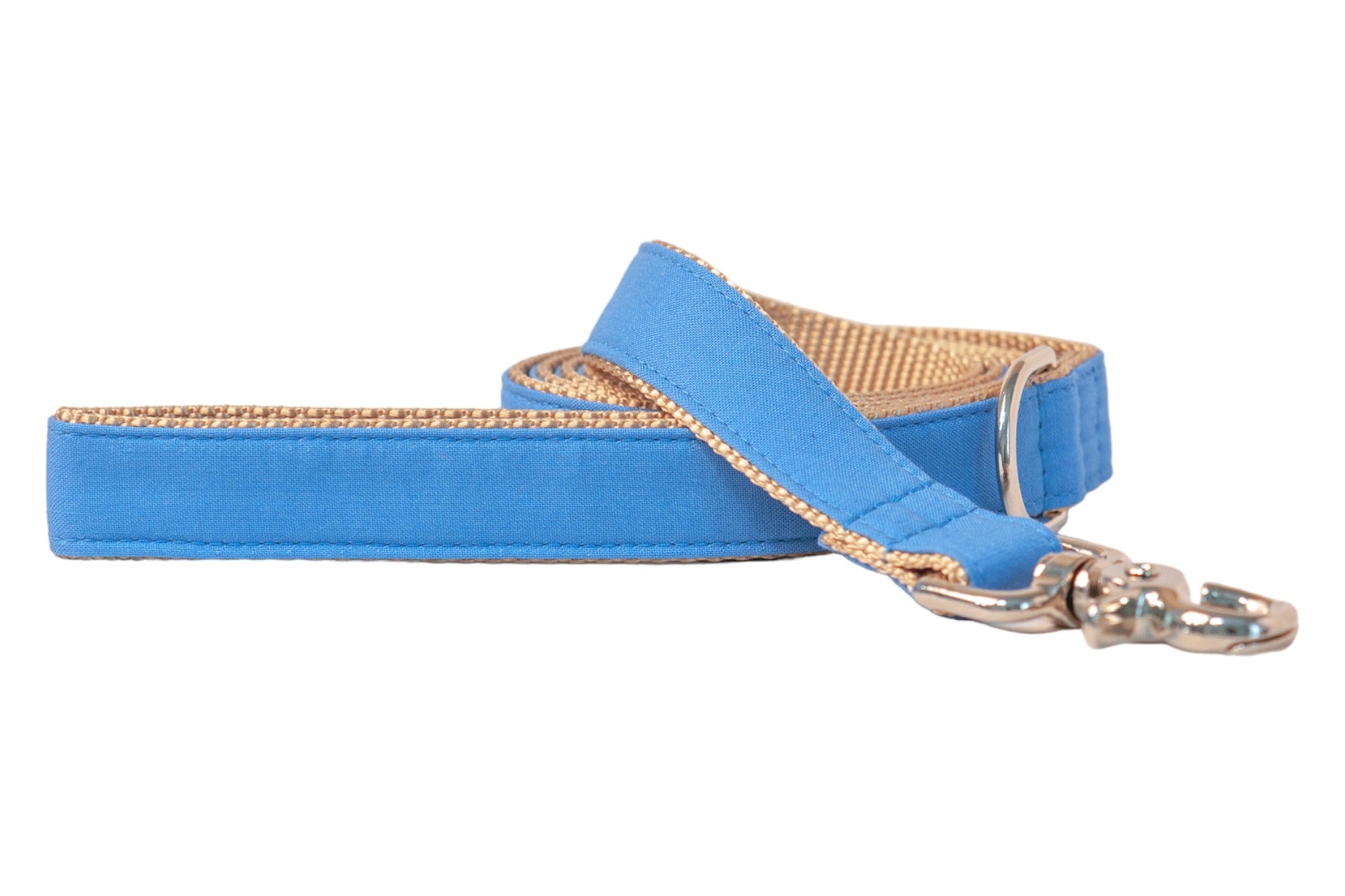 A dog leash in vibrant solid royal blue fabric with a tan woven nylon backing, shown partially coiled. The leash includes neat topstitching, a silver D-ring near the handle, and a polished silver swivel clasp at the end.
