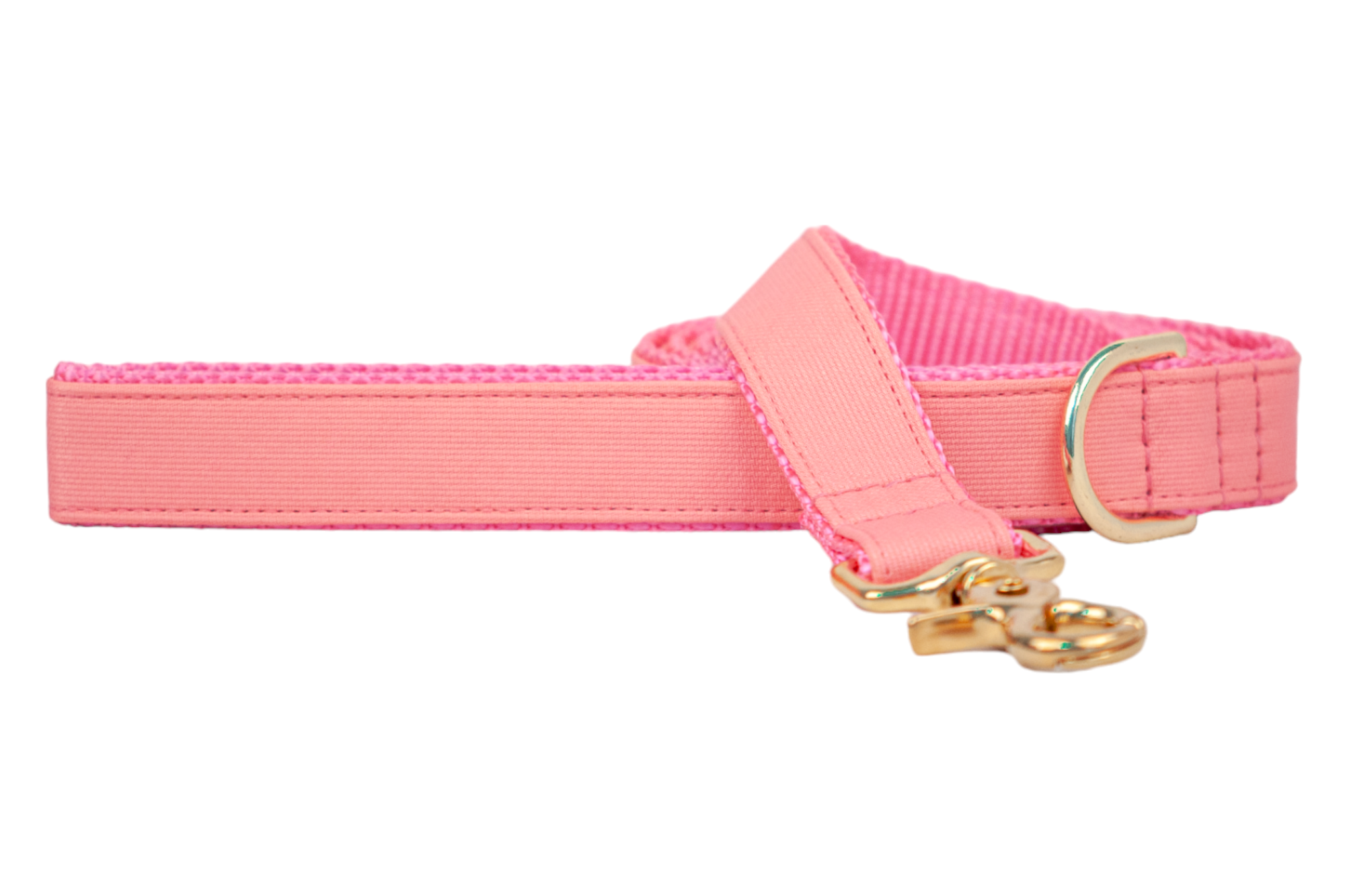 A solid coral dog leash with a ribbed fabric exterior and a durable pink webbed backing. The leash features polished gold-tone hardware, including a swivel clasp and a D-ring near the handle for attaching accessories.