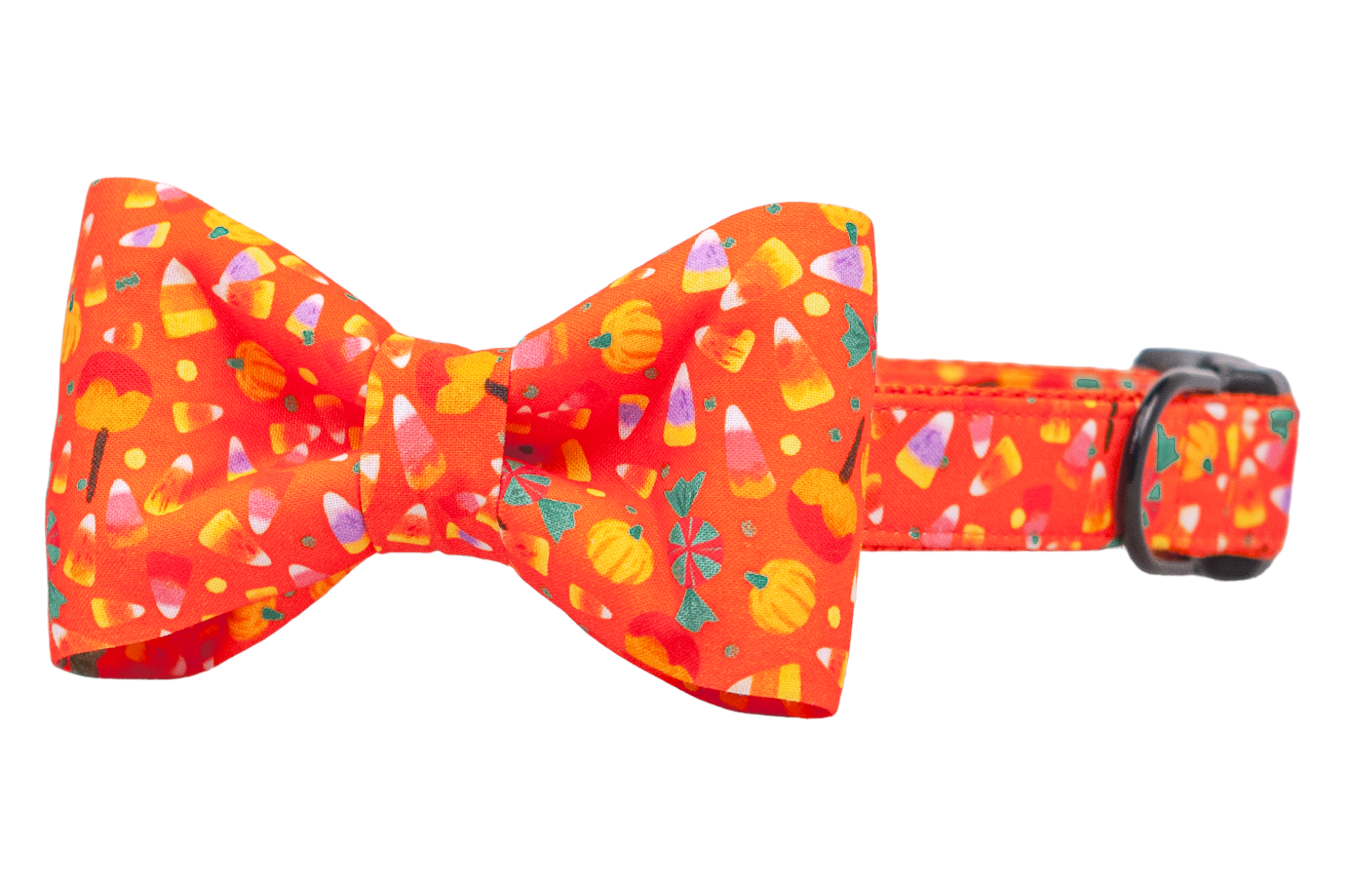 Halloween-themed dog collar with a decorative bow tie, both made from orange fabric with a repeating pattern of candy corn, small pumpkins, caramel apples, and peppermint candy. The collar includes an adjustable strap, a sturdy plastic buckle for secure closure, and a matching metal D-ring.