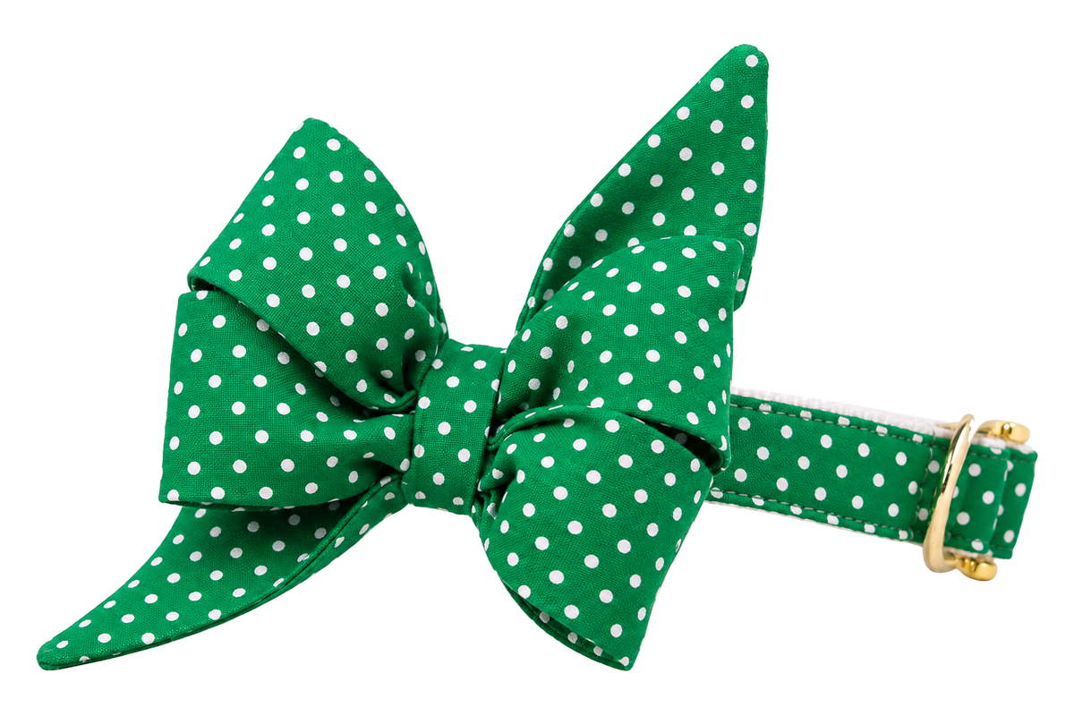 Dog collar featuring a large belle bow in Fairway Green Dots fabric, a kelly green fabric with small white pin dots, attached to a matching Fairway Green Dots collar with a nylon inner lining and gleaming gold hardware, including a D-ring and buckle.