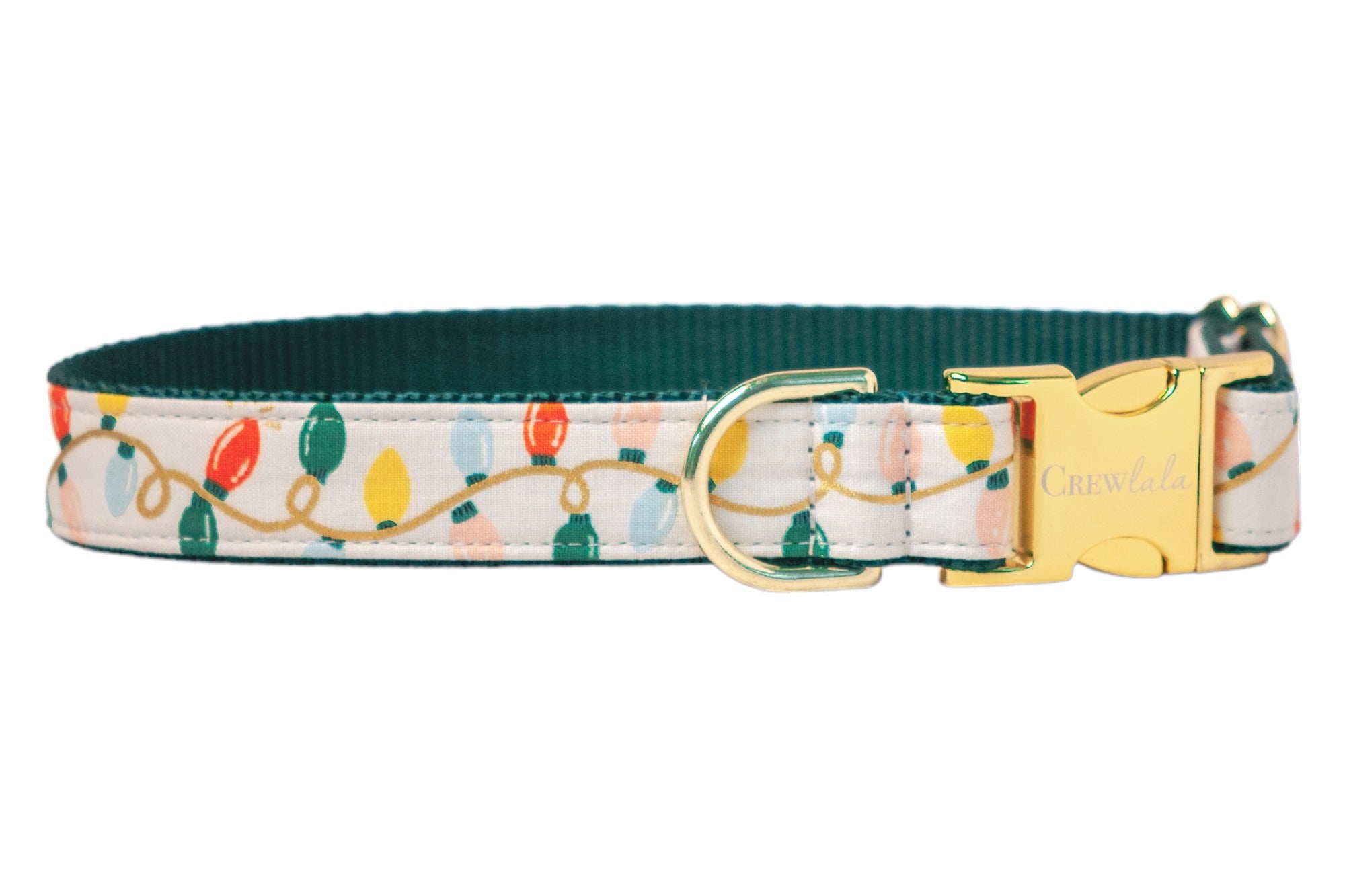 A festive dog collar with a cream-colored fabric exterior printed with colorful holiday string lights in red, green, and other colors connected by a looping cord. The collar features a shiny metal buckle engraved with "Crew LaLa" and a matching D-ring. The inner webbing is a deep green for added structure and contrast.