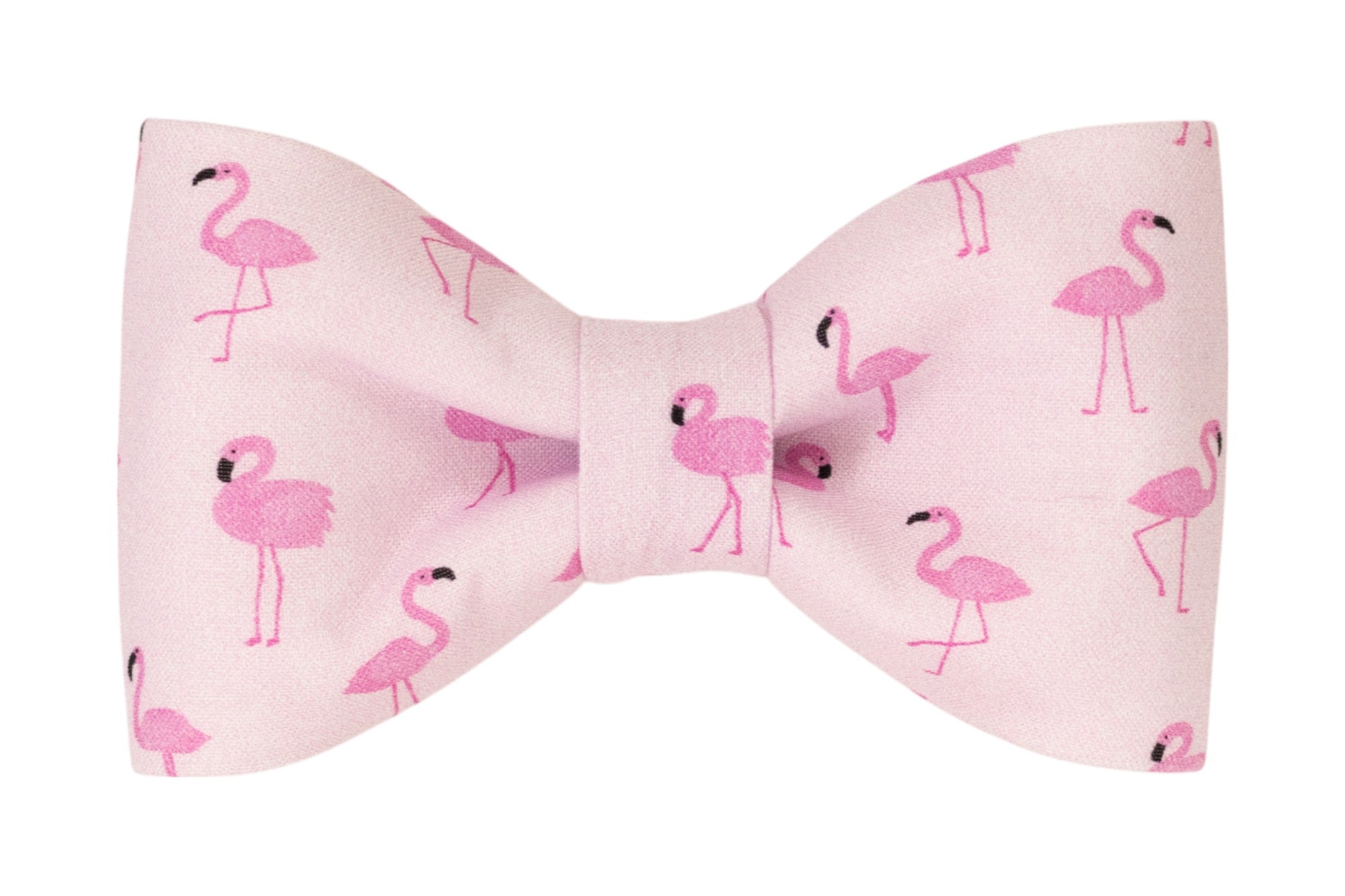 A light pink fabric dog bow tie decorated with bright pink flamingo illustrations in various standing poses. The flamingos feature black beak accents and are evenly scattered across the fabric.