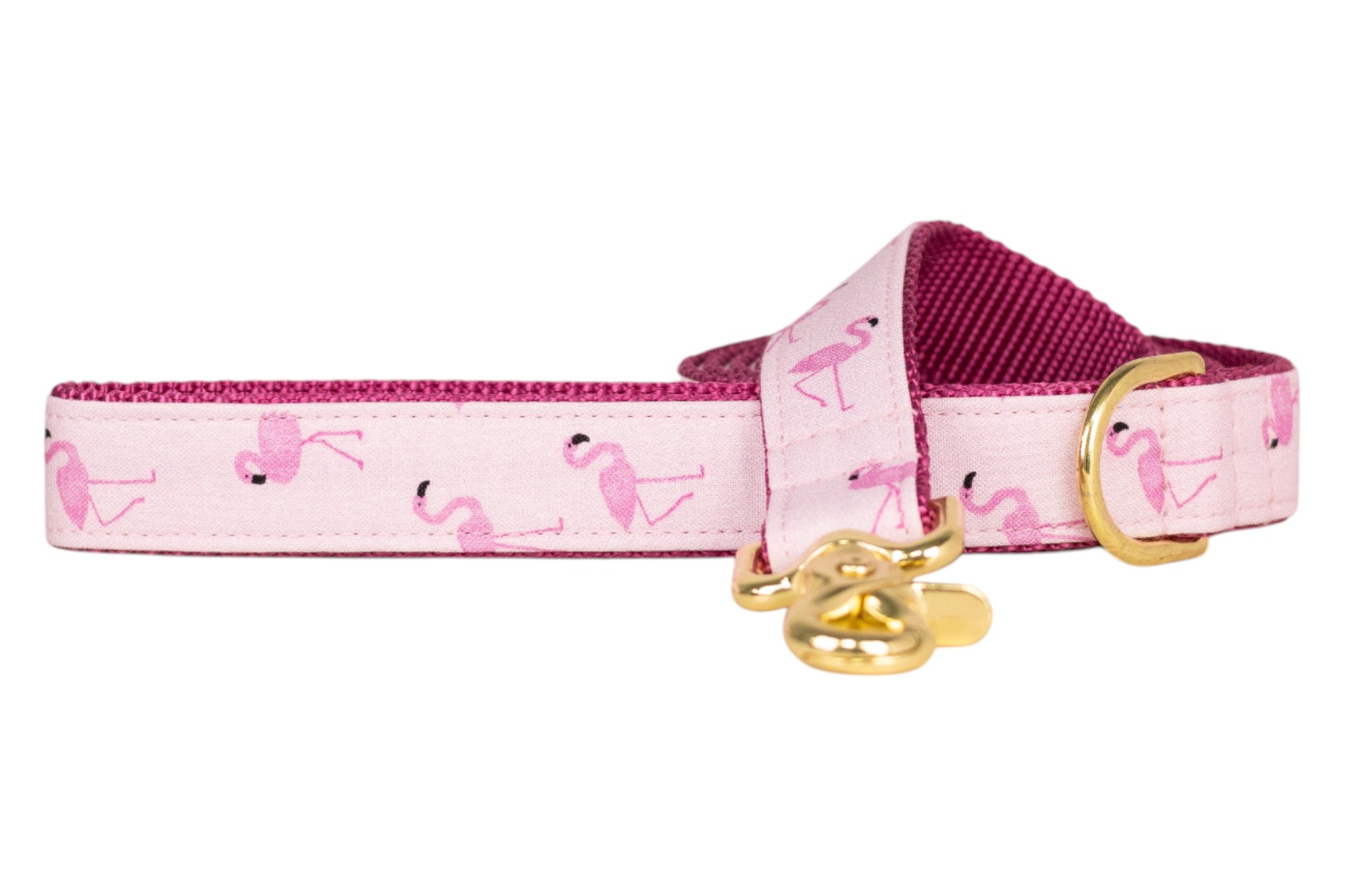 Flamingo-themed dog leash in pastel pink, decorated with pink flamingo illustrations. It has a deep pink woven underside, a gold metal D-ring, and a matching gold clasp for secure attachment.