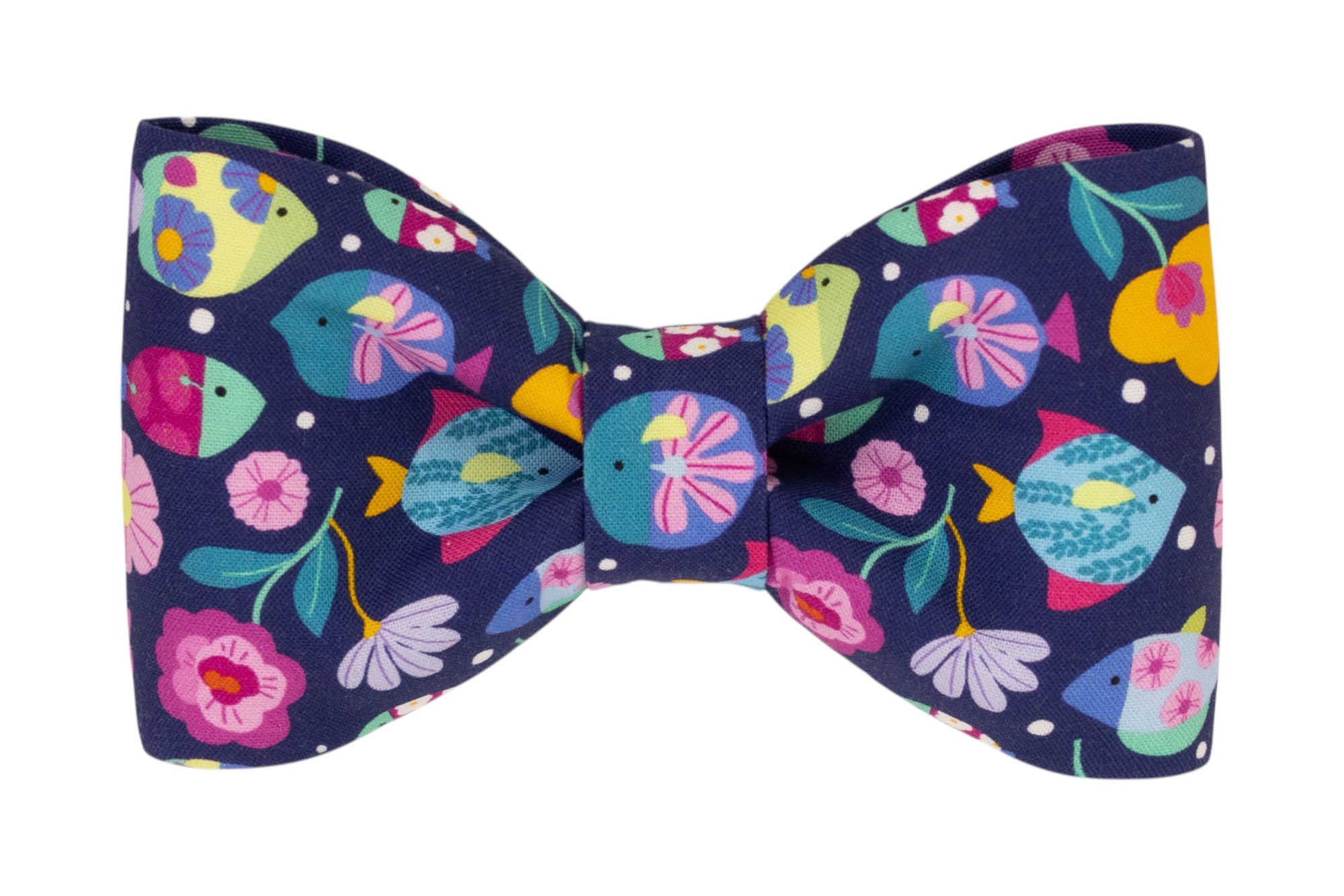 Close-up of a navy blue dog bow tie featuring a whimsical print of multicolored fish, tropical flowers, and dotted accents. The pattern is lively and eye-catching.