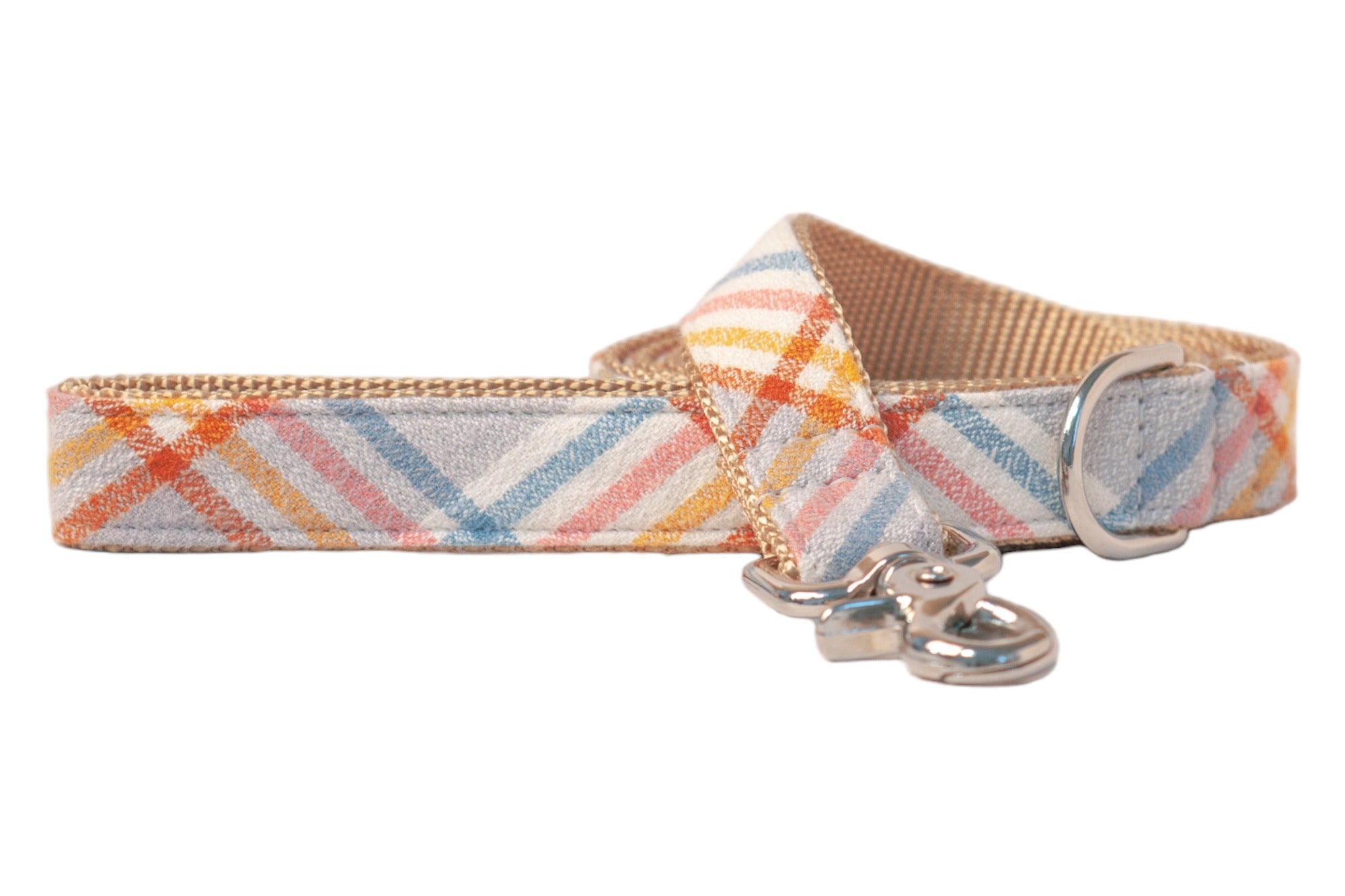 Close-up of a stylish dog leash in a light plaid flannel fabric with warm and cool tones arranged in diagonal stripes. The dog leash features beige backing, strong stitching along the edges, a D-ring, and a metal hook clasp at the end.