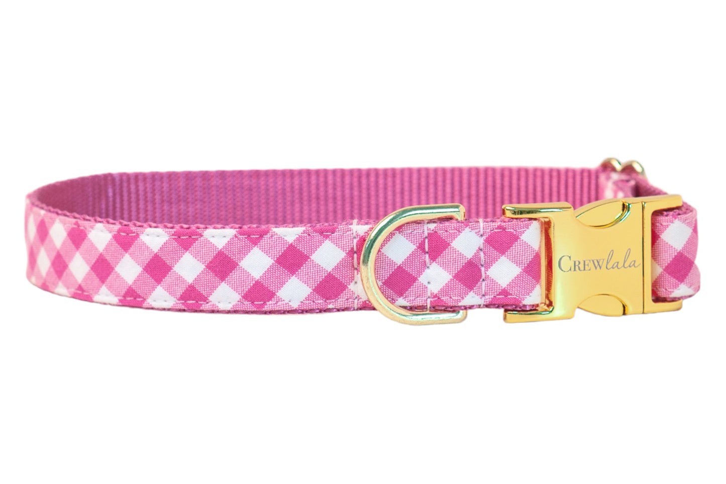 Bright fuchsia and white plaid fabric dog collar backed by durable pink nylon webbing. Accented with gold-finish hardware including a branded buckle and secure leash ring.