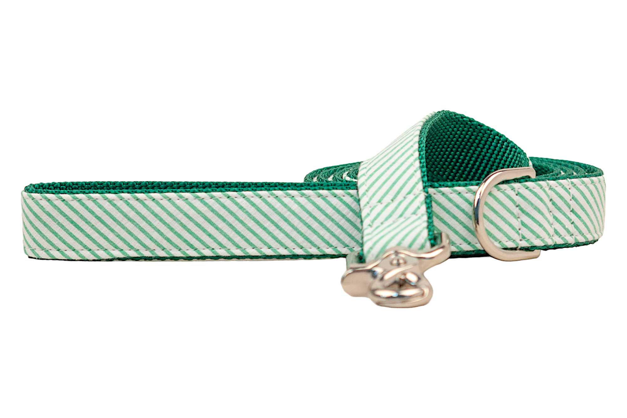A green and white striped seersucker leash with a textured green nylon backing, shown coiled with the metal clasp resting in front. The seersucker fabric overlay features diagonal stripes and reinforced stitching, while a silver-tone D-ring is visible near the handle.