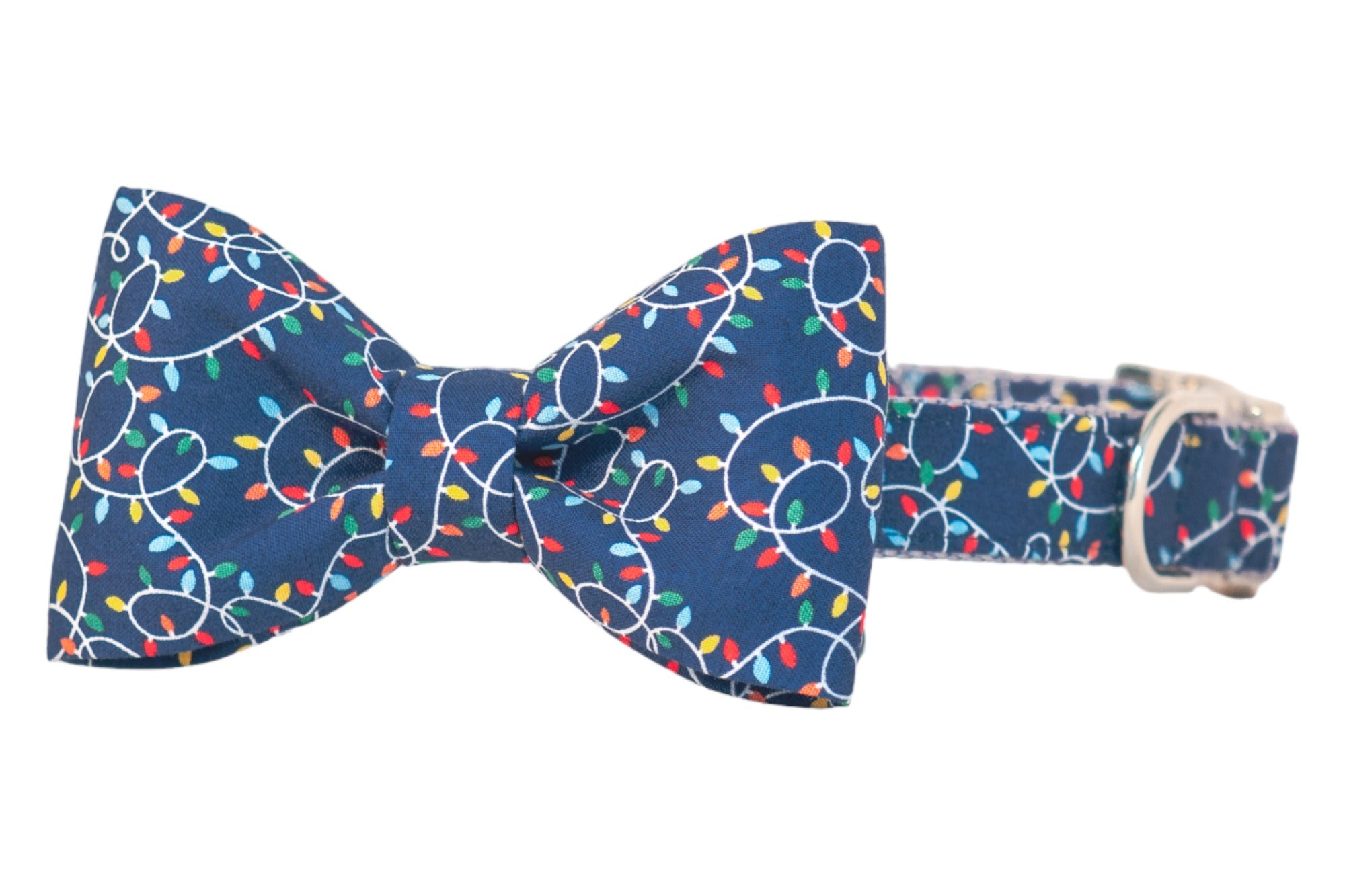 Festive dog bow tie collar featuring a navy background patterned with strings of colored holiday lights. Attached bow tie matches the collar fabric. Metal buckle and D-ring add a polished finish.