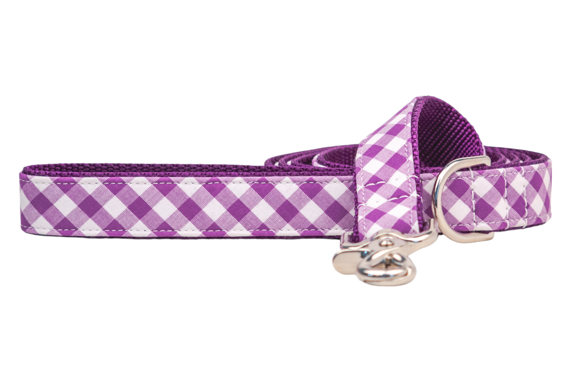 A stylish dog leash featuring a purple checkered pattern, made from a durable fabric material with reinforced stitching along the edges. The leash is coiled neatly, showing a metal swivel snap hook and a matching silver D-ring near the handle.