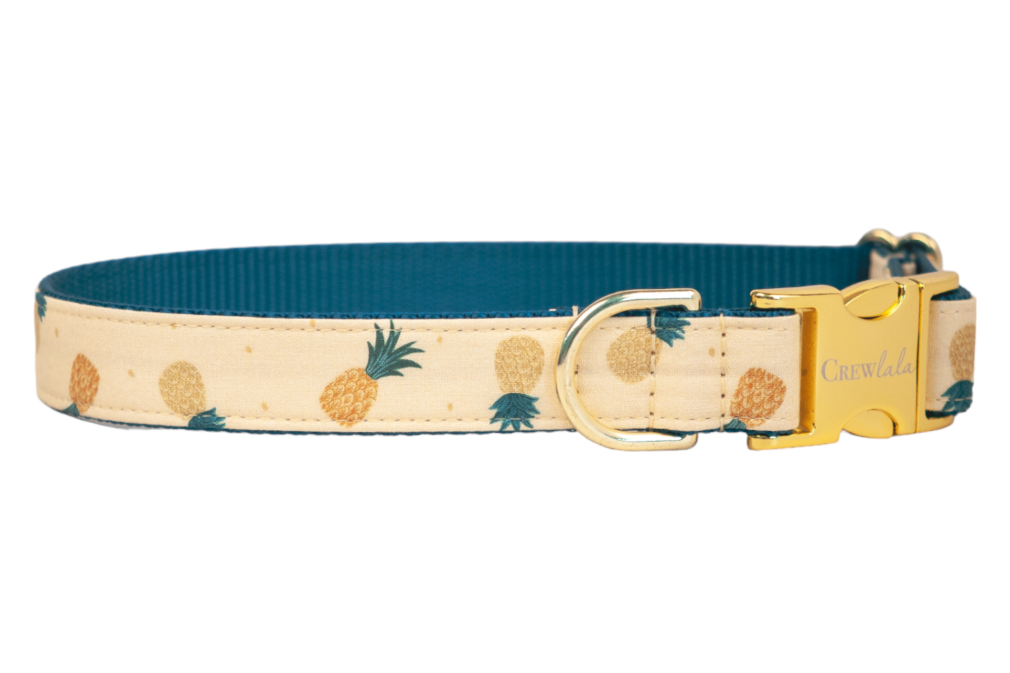 Tropical-themed dog collar with a soft tan fabric exterior patterned with stylized pineapples in varying shades of yellow and orange. The collar has a rich teal woven underside and gold metal accents, including a branded side-release buckle and matching D-ring.