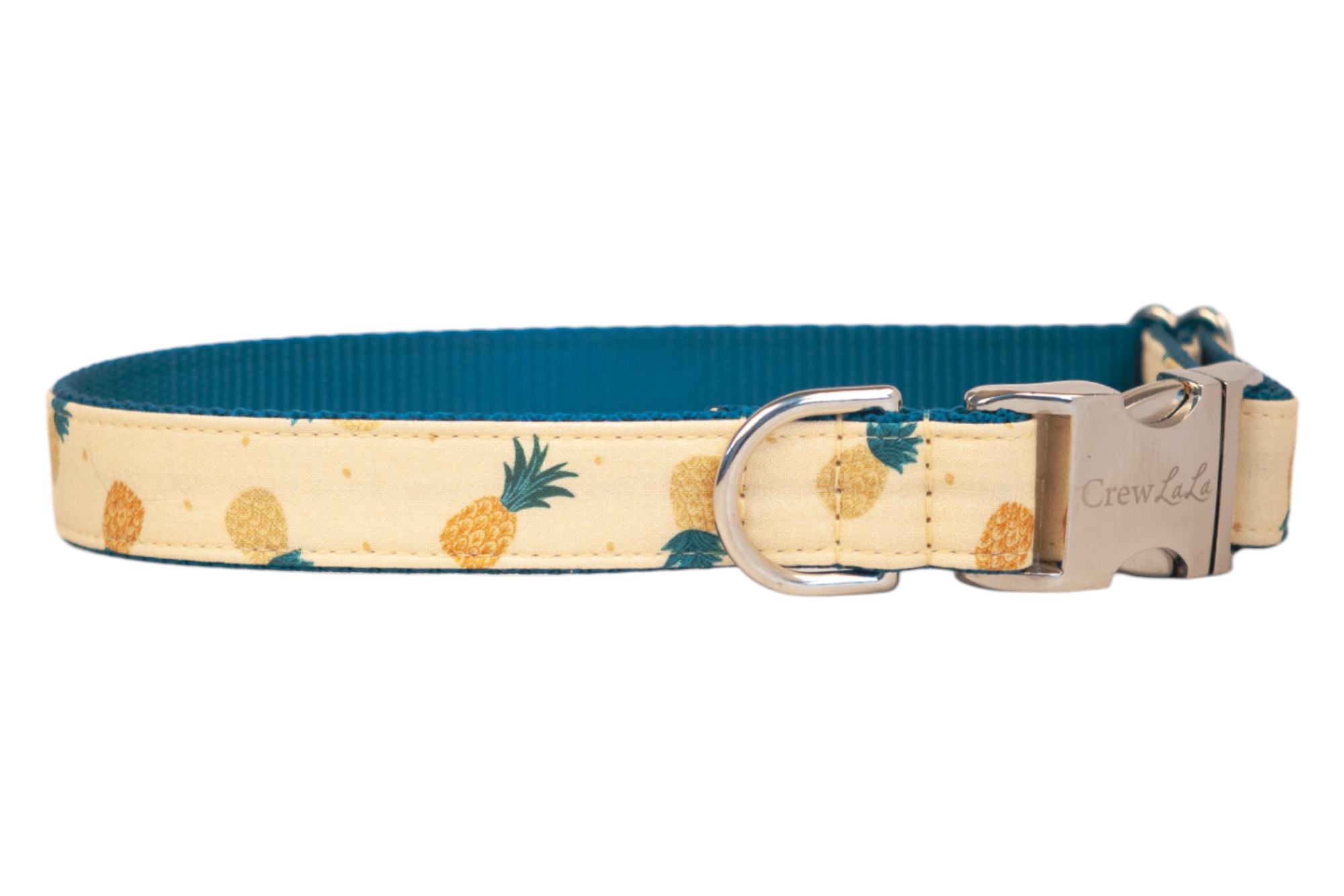 Tropical-themed dog collar with a soft tan fabric exterior patterned with stylized pineapples in varying shades of yellow and orange. The collar has a rich teal woven underside and silver metal accents, including a branded side-release buckle and matching D-ring.