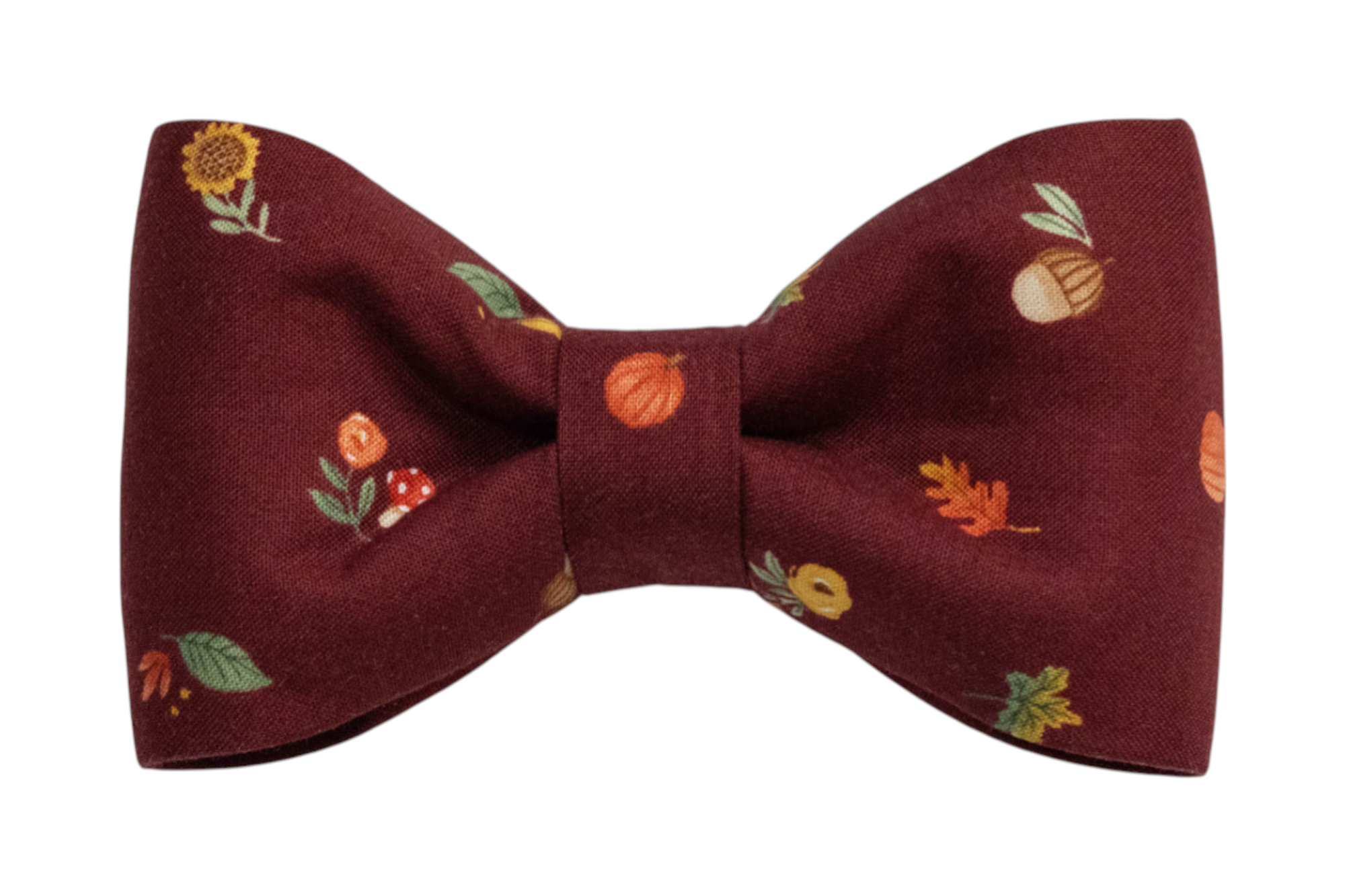 Seasonal bow tie for dogs in deep red fabric, adorned with whimsical fall-themed illustrations such as toadstools, sunflowers, and foliage.