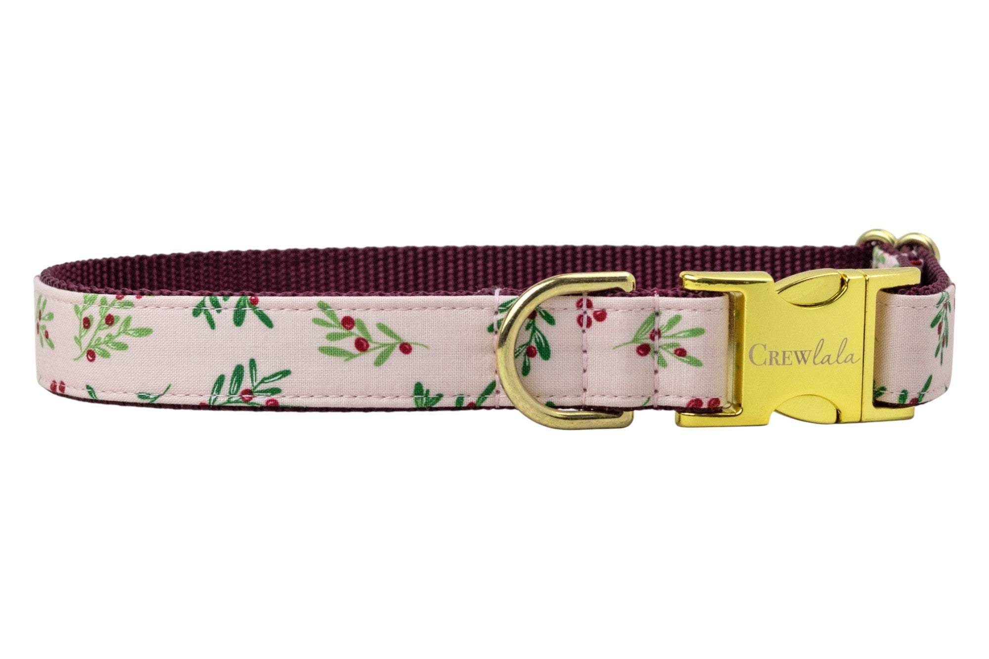 Adjustable dog collar with a soft pink fabric exterior with leafy sprigs and small berries. The inner lining is made of durable nylon webbing. The collar features polished hardware, including a side-release buckle engraved with the brand name “Crewlala,” a metal D-ring, and double-loop sizing hardware.