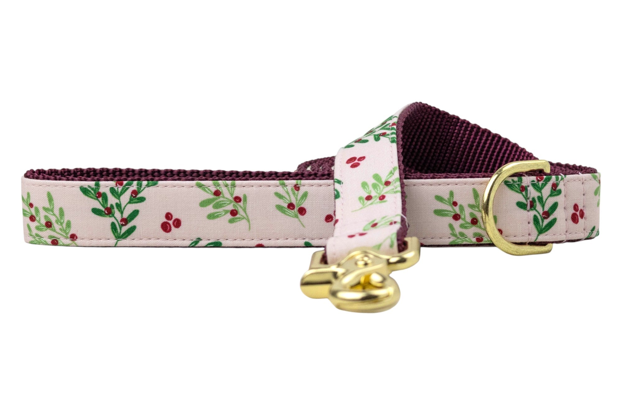 A dog leash featuring a soft pink fabric exterior with a repeating pattern of leafy branches and clusters of small berries. The inner lining is a sturdy nylon webbing, providing durability and contrast. The leash includes shiny hardware: a swivel snap hook and a D-ring near the handle loop for attaching accessories.