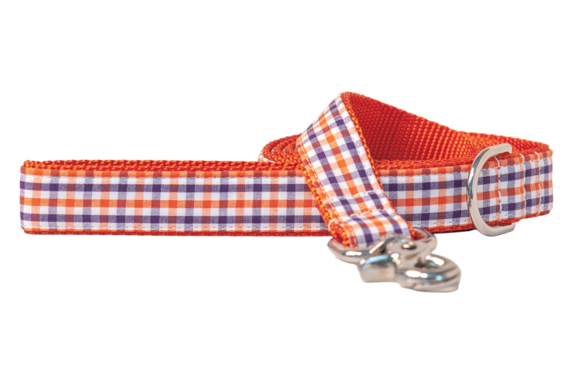 A colorful dog leash made of durable woven material, featuring a vibrant orange nylon interior and an outer layer with a neat plaid pattern in alternating rows. It includes a polished swivel snap hook and a metal D-ring for attachments.