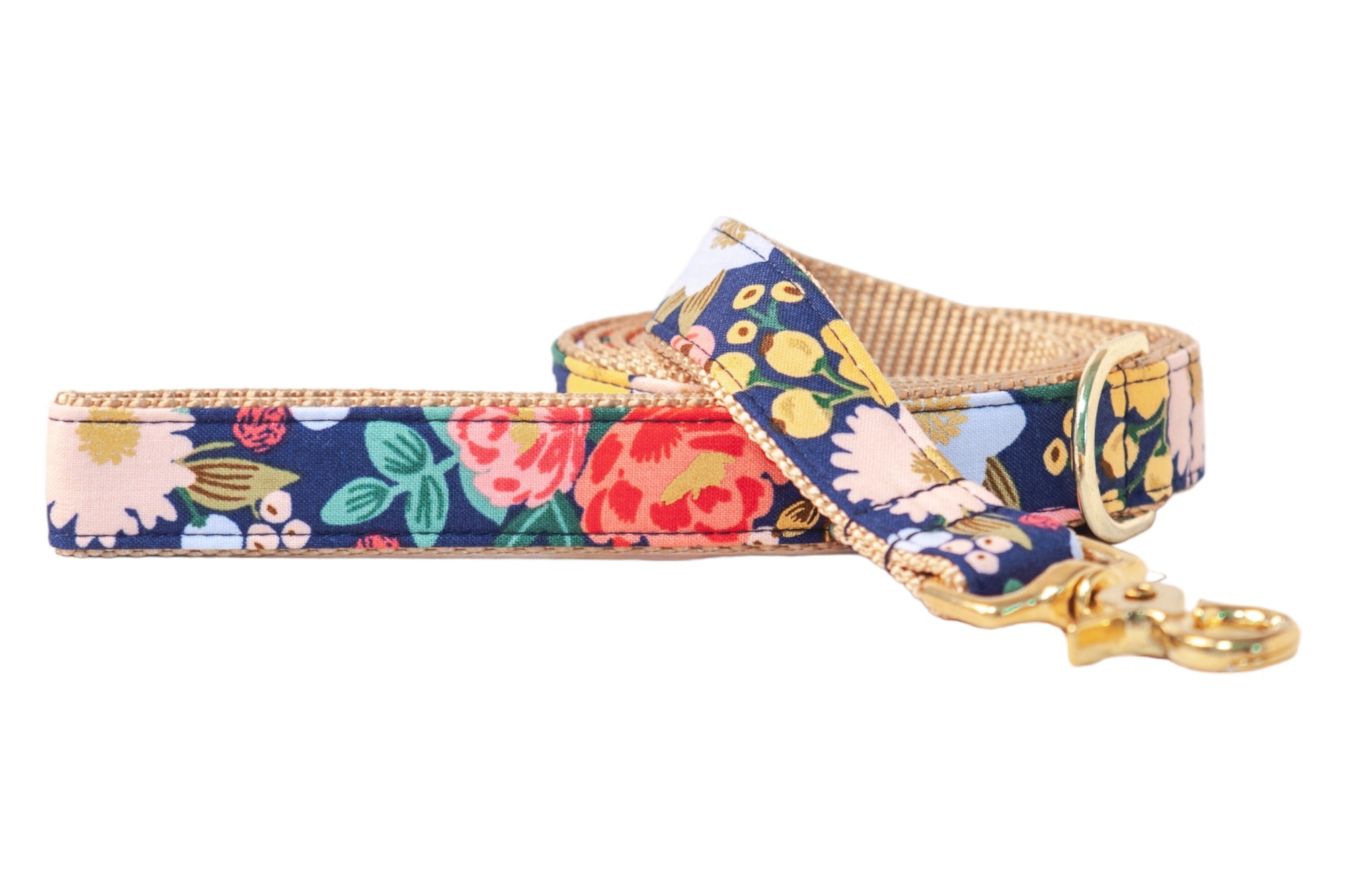 Dog leash featuring a navy blue background with a vibrant floral pattern. The leash is lined with woven nylon webbing for durability and finished with a shiny metal clasp and matching D-ring near the handle.