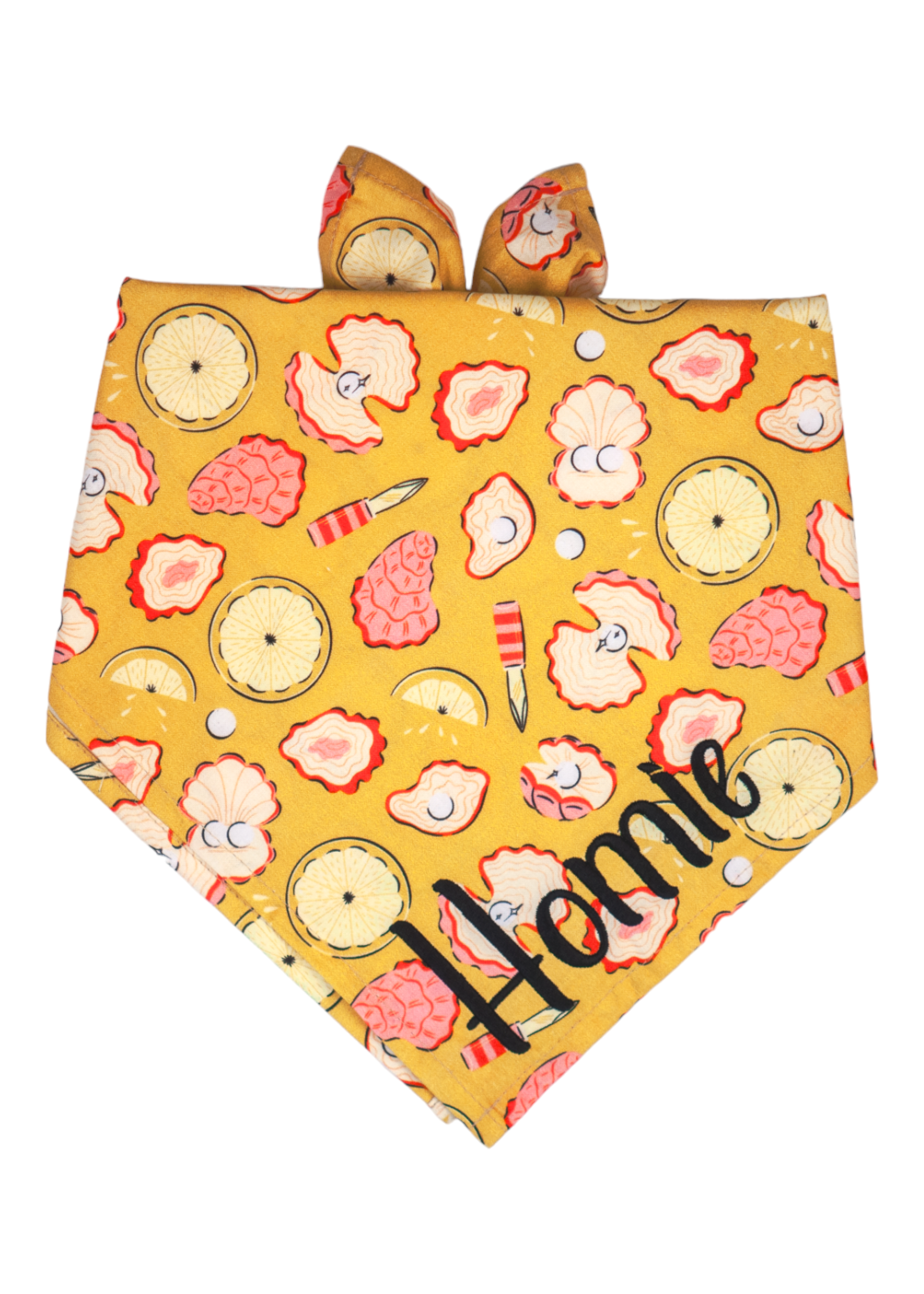 Bright yellow dog bandana decorated with a seafood pattern of illustrated oysters in pink and cream tones, alongside pearls, halved lemons and tiny oyster knives. The bottom corner features the name "Homie" embroidered in large, playful black script.