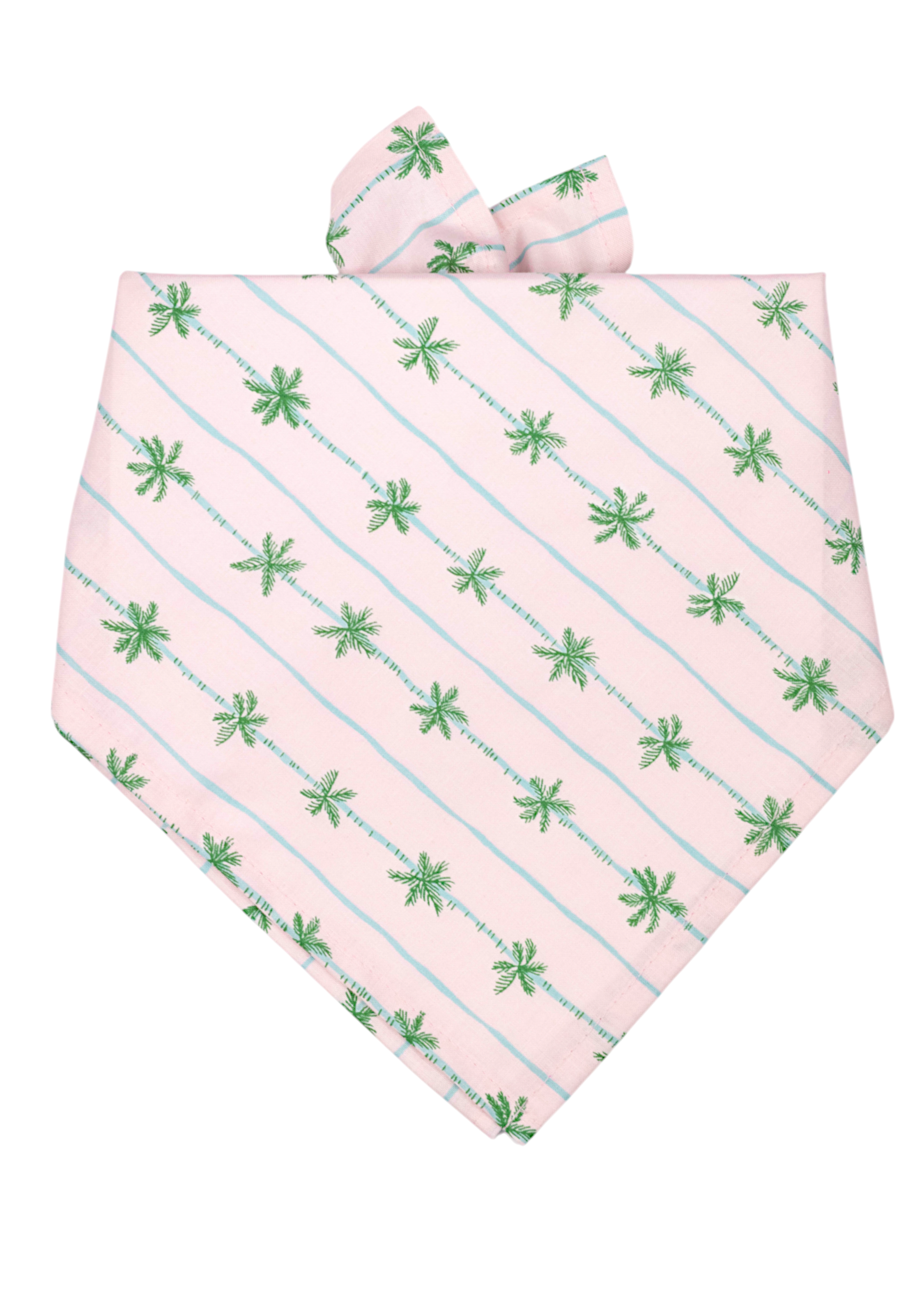 Soft pink bandana for dogs, decorated with slanted rows of small green palm trees and light blue lines, neatly folded.