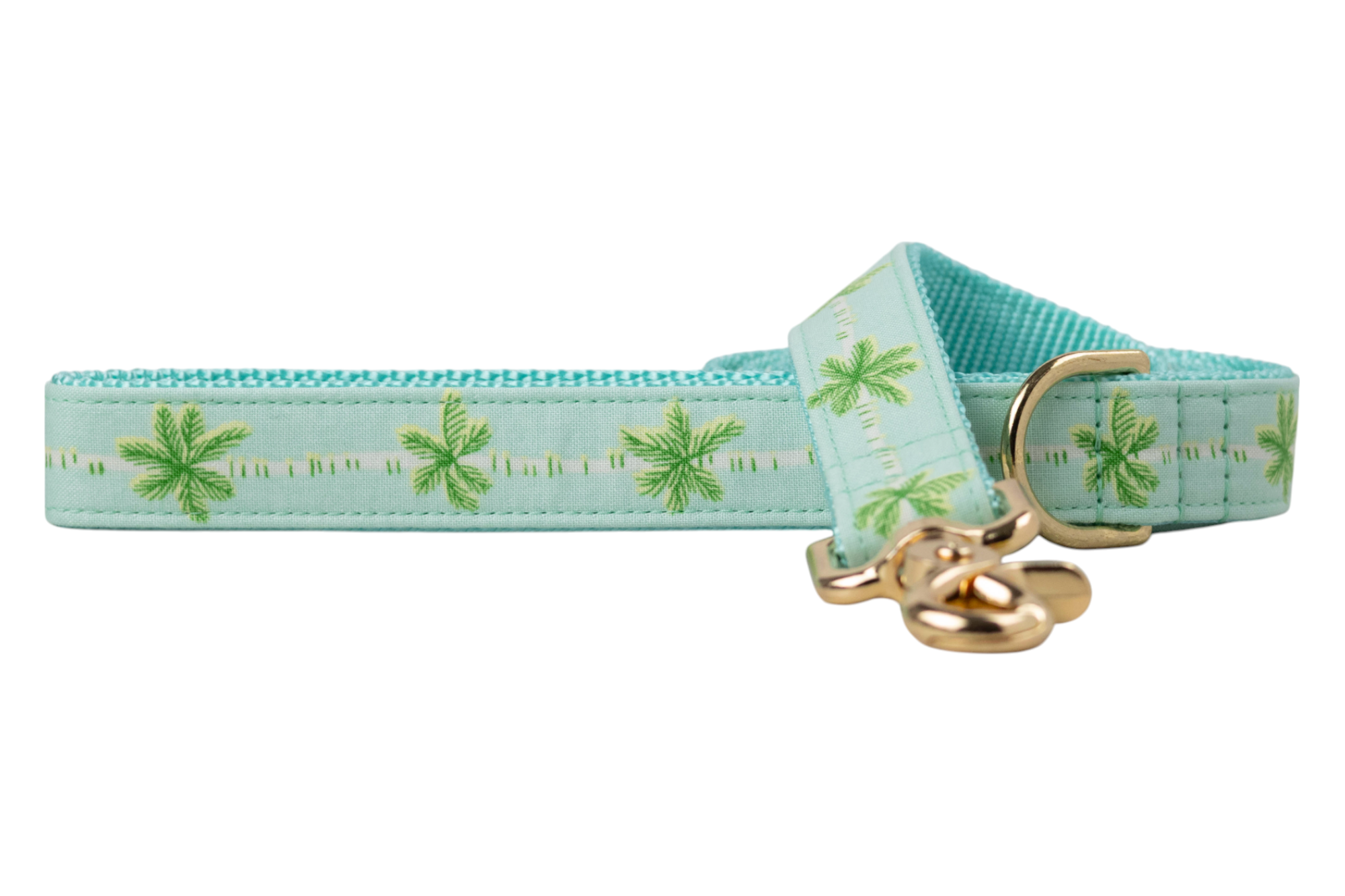 A stylish dog leash made from aqua blue fabric decorated with repeating green palm tree motifs. The leash has teal nylon backing for added durability and includes a gold-tone swivel hook and D-ring. The fabric is neatly stitched, and the tropical pattern adds a breezy, vacation-inspired flair.