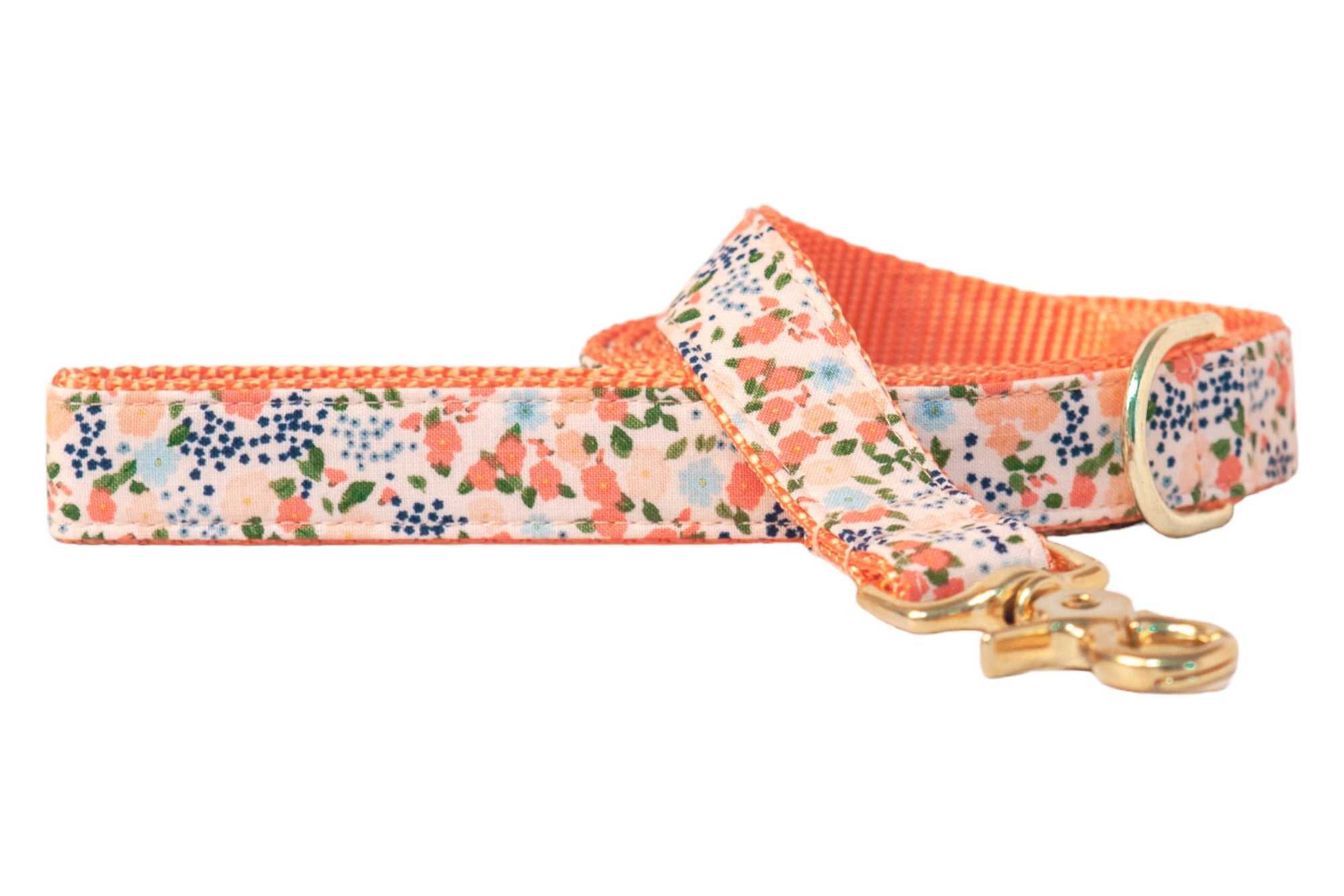 Dog leash with a pink fabric base patterned with clusters of flowers with leaves, lined with textured nylon webbing, and finished with a metal clasp and D-ring.