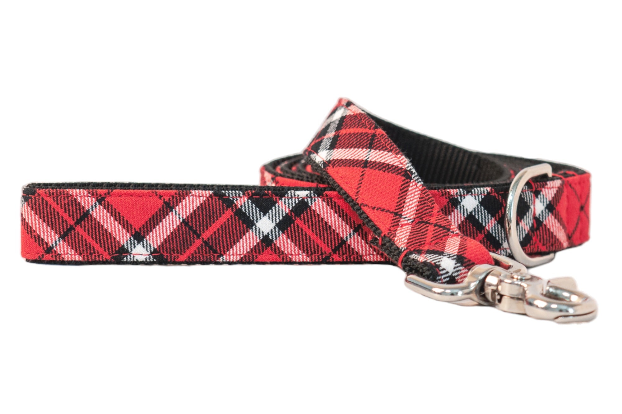 A festive and functional dog leash featuring a classic red plaid pattern with intersecting black and white lines, stitched onto black webbing for added durability, and finished with a swivel snap hook and D-ring for accessory attachment.