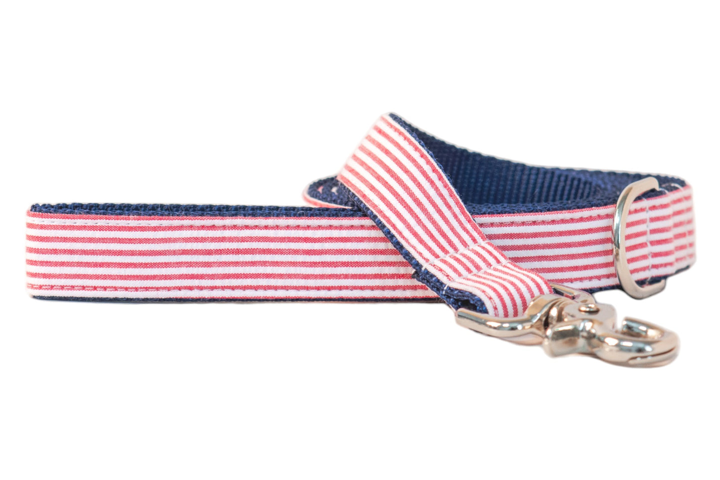 Patriotic-themed dog leash with a red-and-white striped seersucker front, navy blue interior webbing, and a shiny silver clip hook, blending classic Americana style with durable construction.