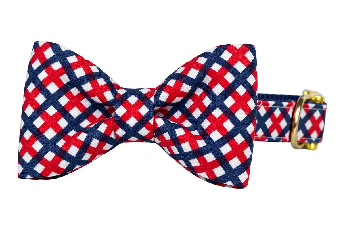 Classic dog collar featuring a Patriotic Plaid fabric bow tie, a navy blue, red and white lattice check, attached to a matching Patriotic Plaid collar with a nylon inner lining and gleaming gold hardware, including a D-ring and buckle.