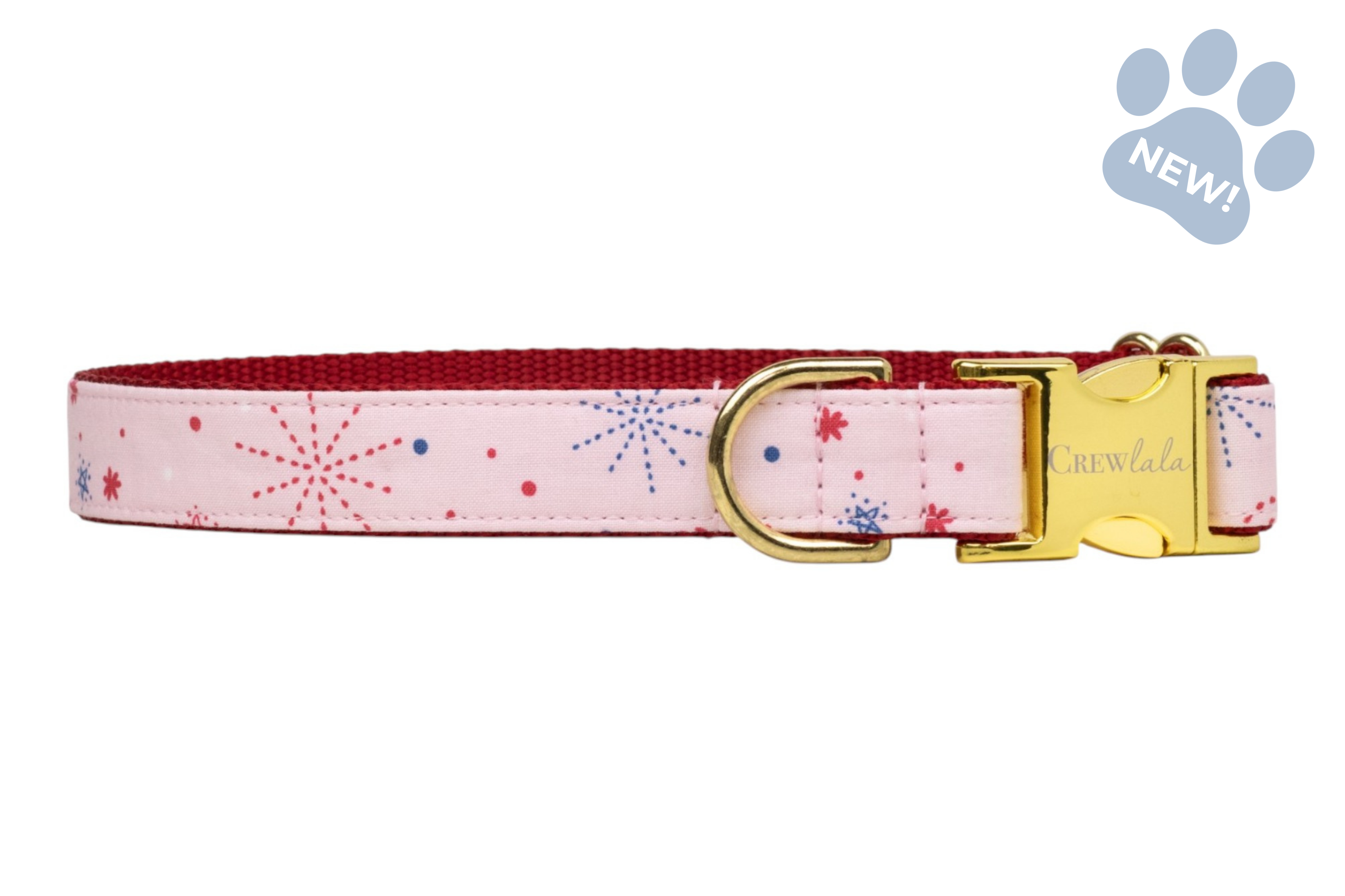 Pink fabric dog collar with scattered red and blue firework-style bursts, accented by a polished gold buckle and ring.